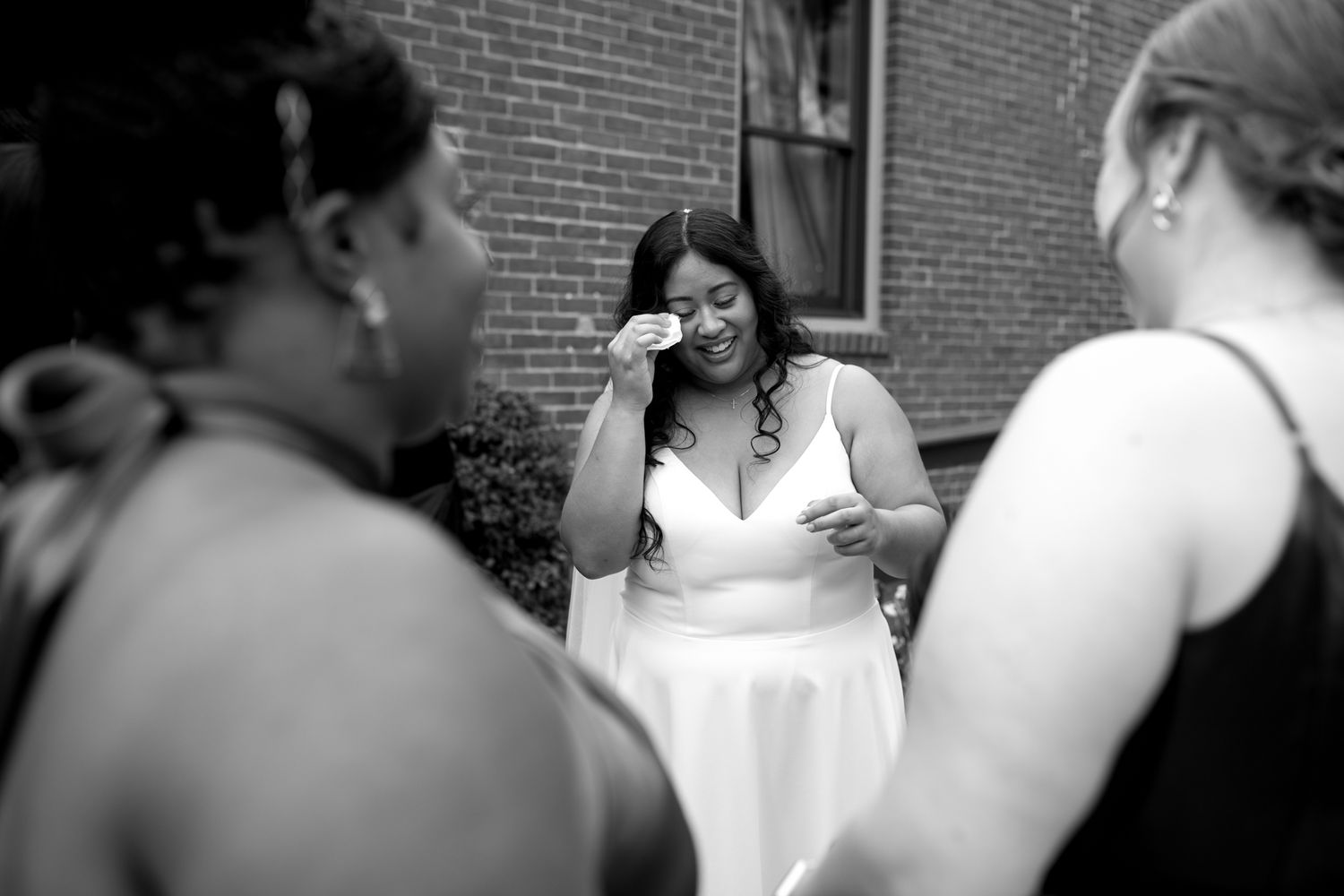 A black and white candid moment showing several people conversing outside a brick building.