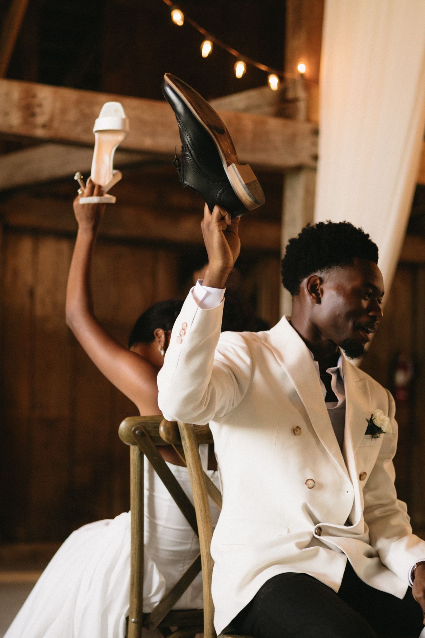 Joyful celebration dance in white attire under rustic barn lighting.