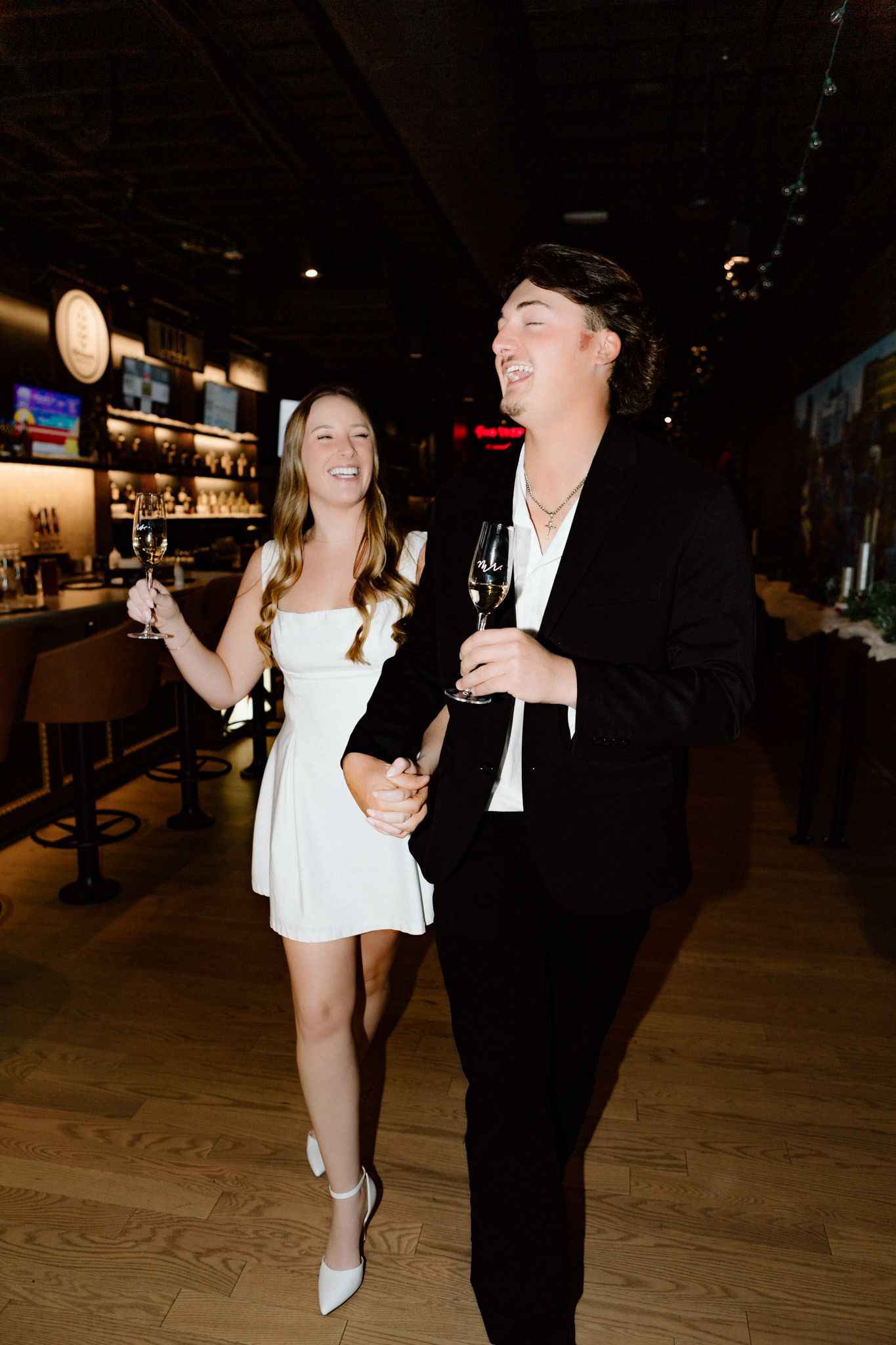 Engaged couple celebrating with a glass of champagne, sharing a joyful moment and laughter in downtown Louisville