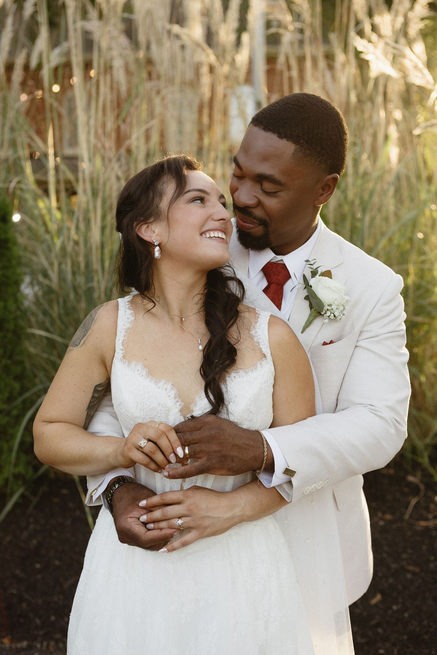 Romantic wedding couple sharing intimate moments outdoors near tall ornamental grasses.