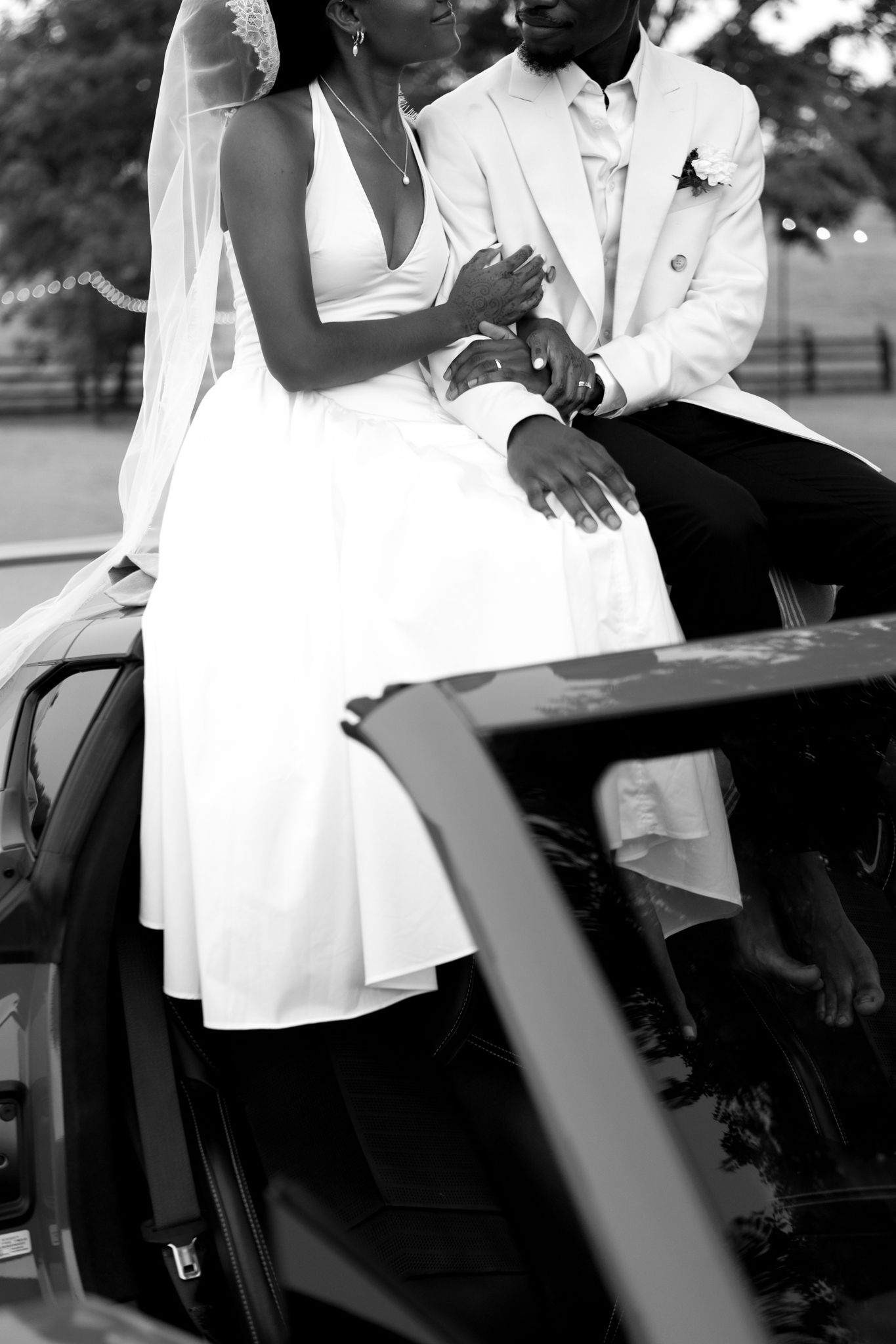 Stylish couple poses for romantic black and white photos by a luxury car.