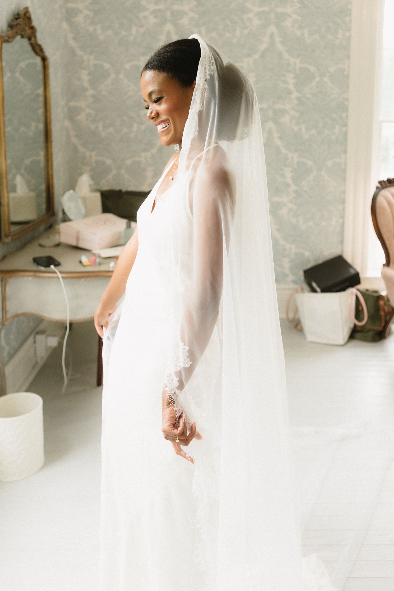 Elegant portrait session with a flowing white bridal veil captured in a bright interior setting.