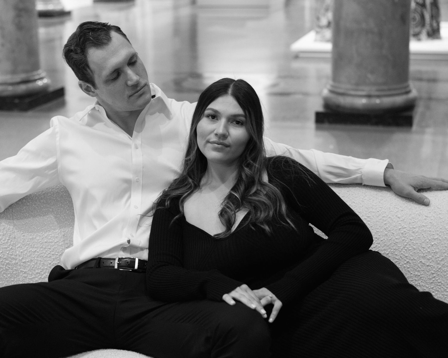 Engaged couple in downtown Louisville, with the woman smiling and showing her engagement ring while embracing her fiancé