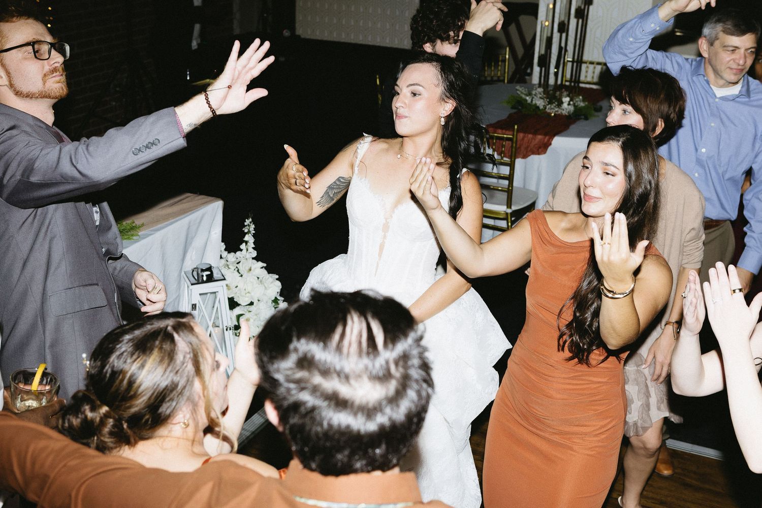 Wedding reception dance floor scene with guests celebrating and dancing.