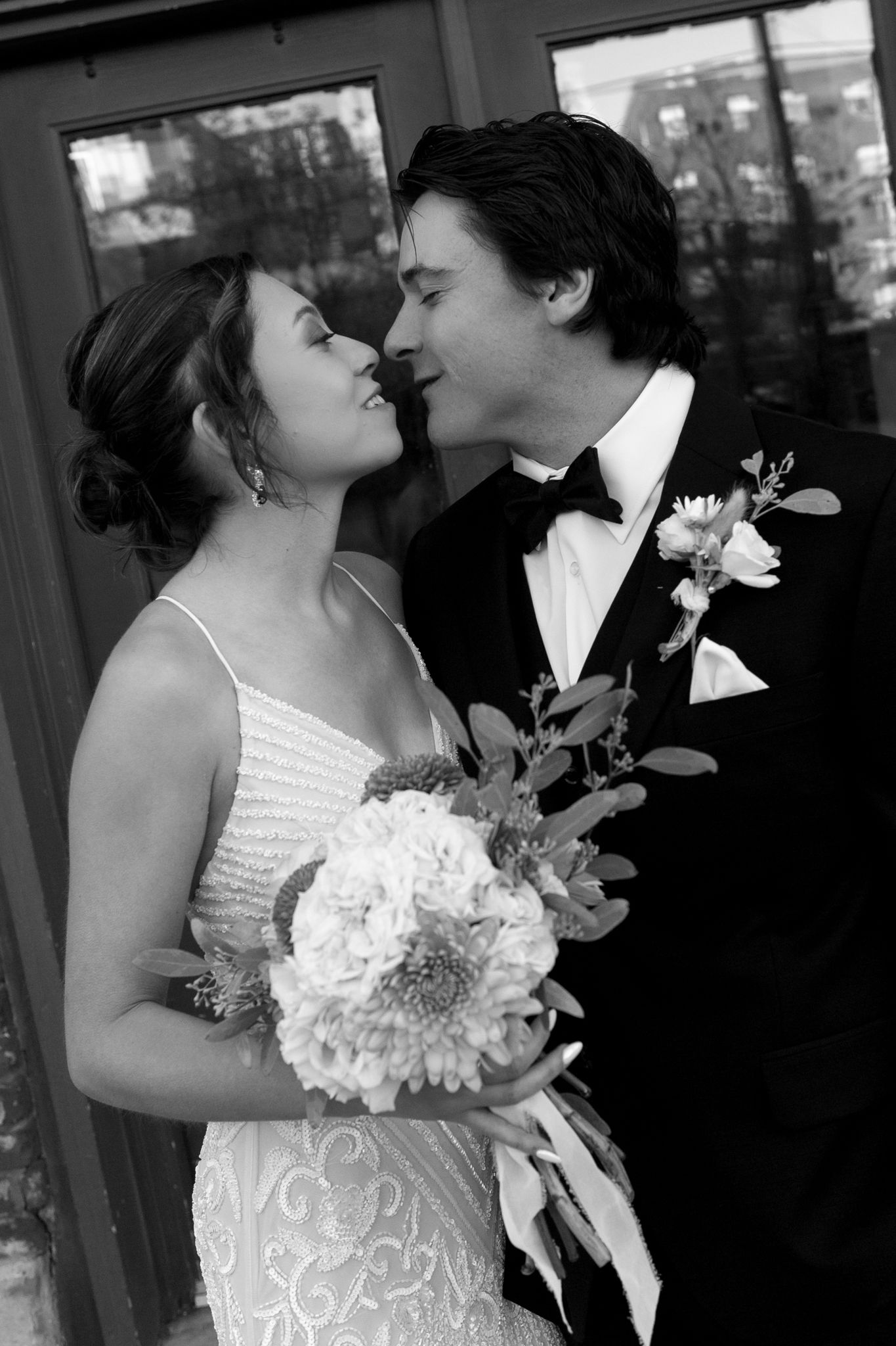 A romantic black and white photo of newlyweds with a bridal bouquet.