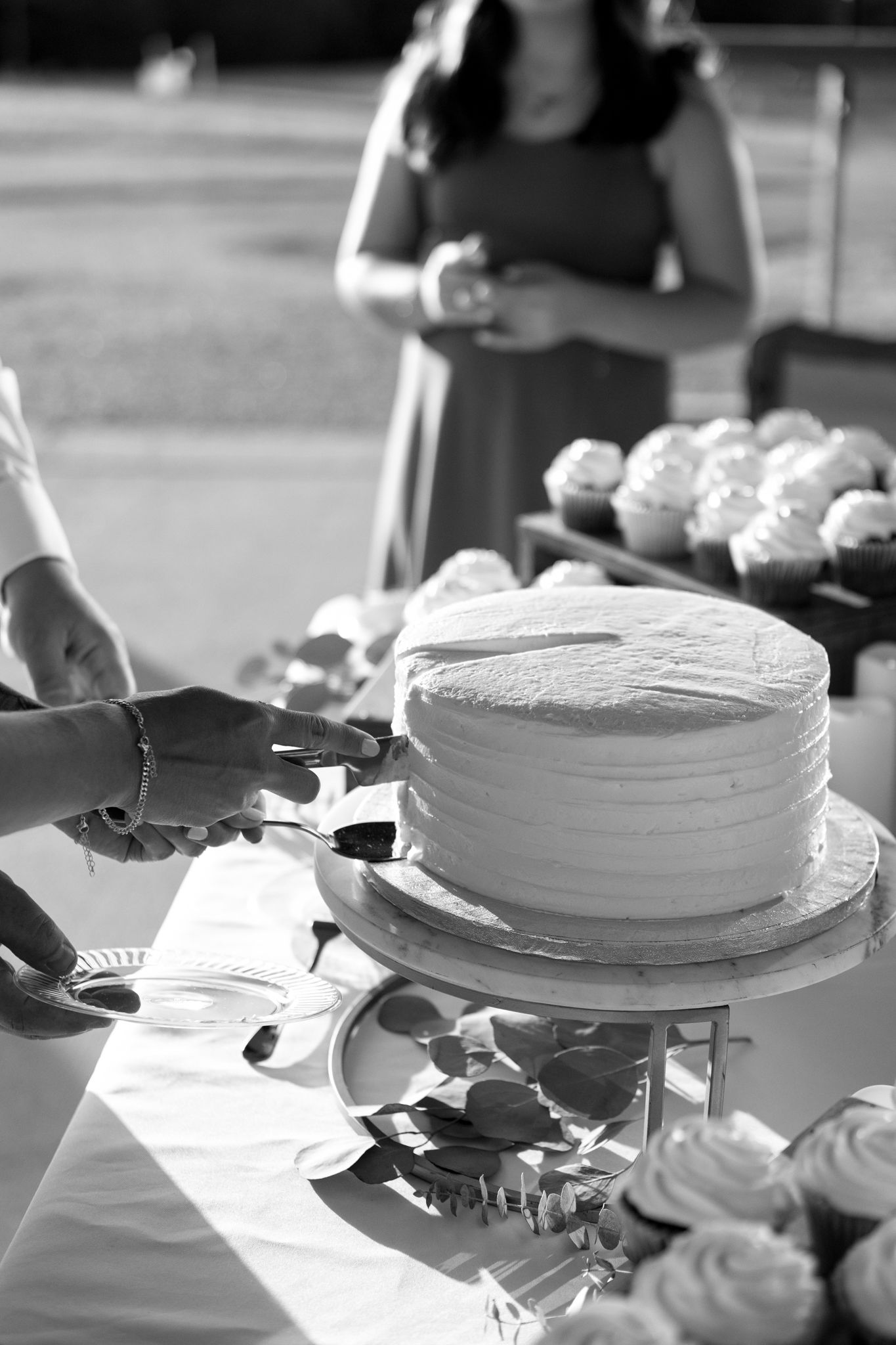 White frosted wedding cakes displayed on tables being prepared for service.