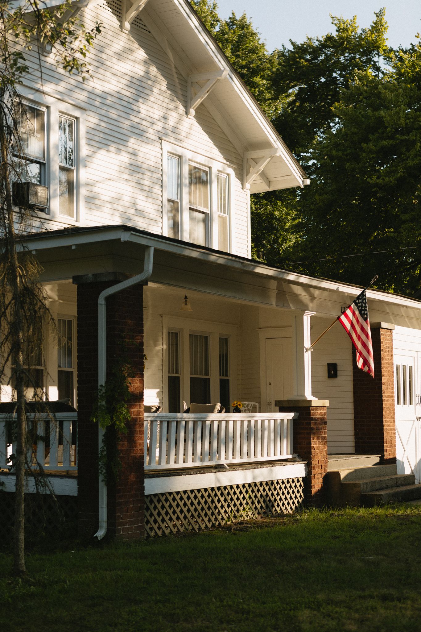 historic white house with beautiful lawn and flag in the front yard