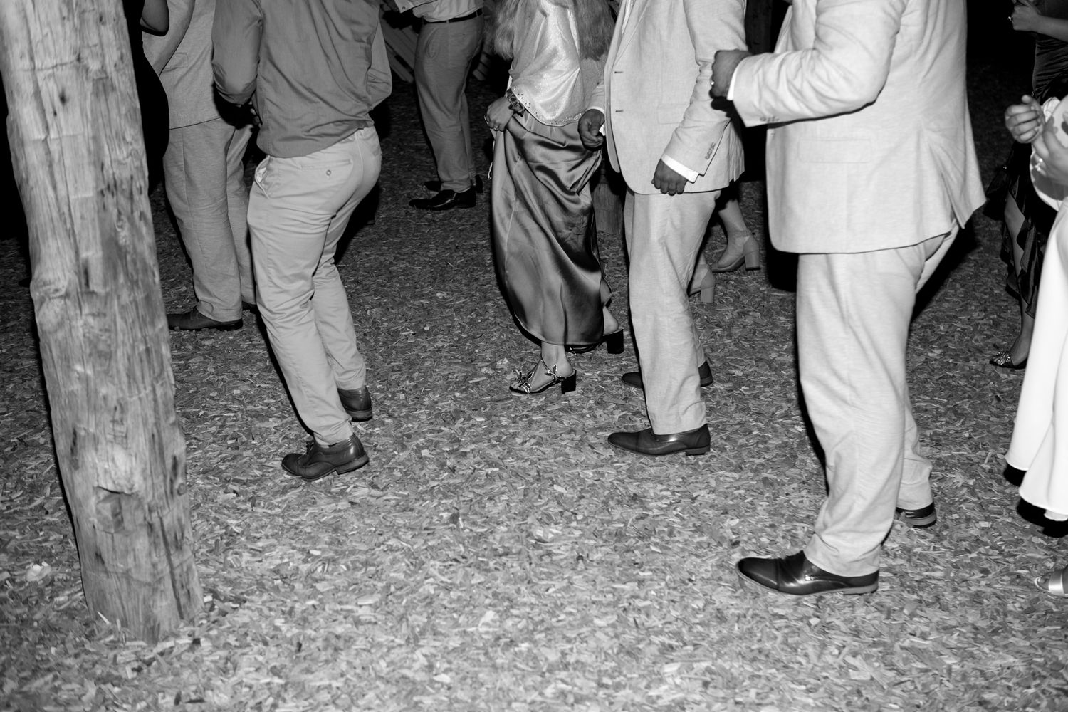 A group of people dancing and celebrating at night under string lights at an outdoor party.