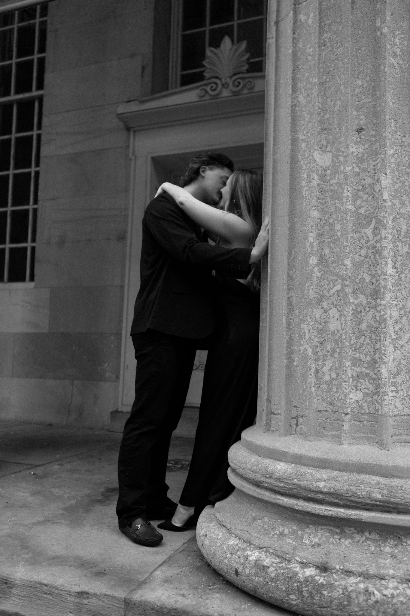 Black and white photo of an engaged couple embracing and smiling, sharing an intimate moment in downtown Louisville