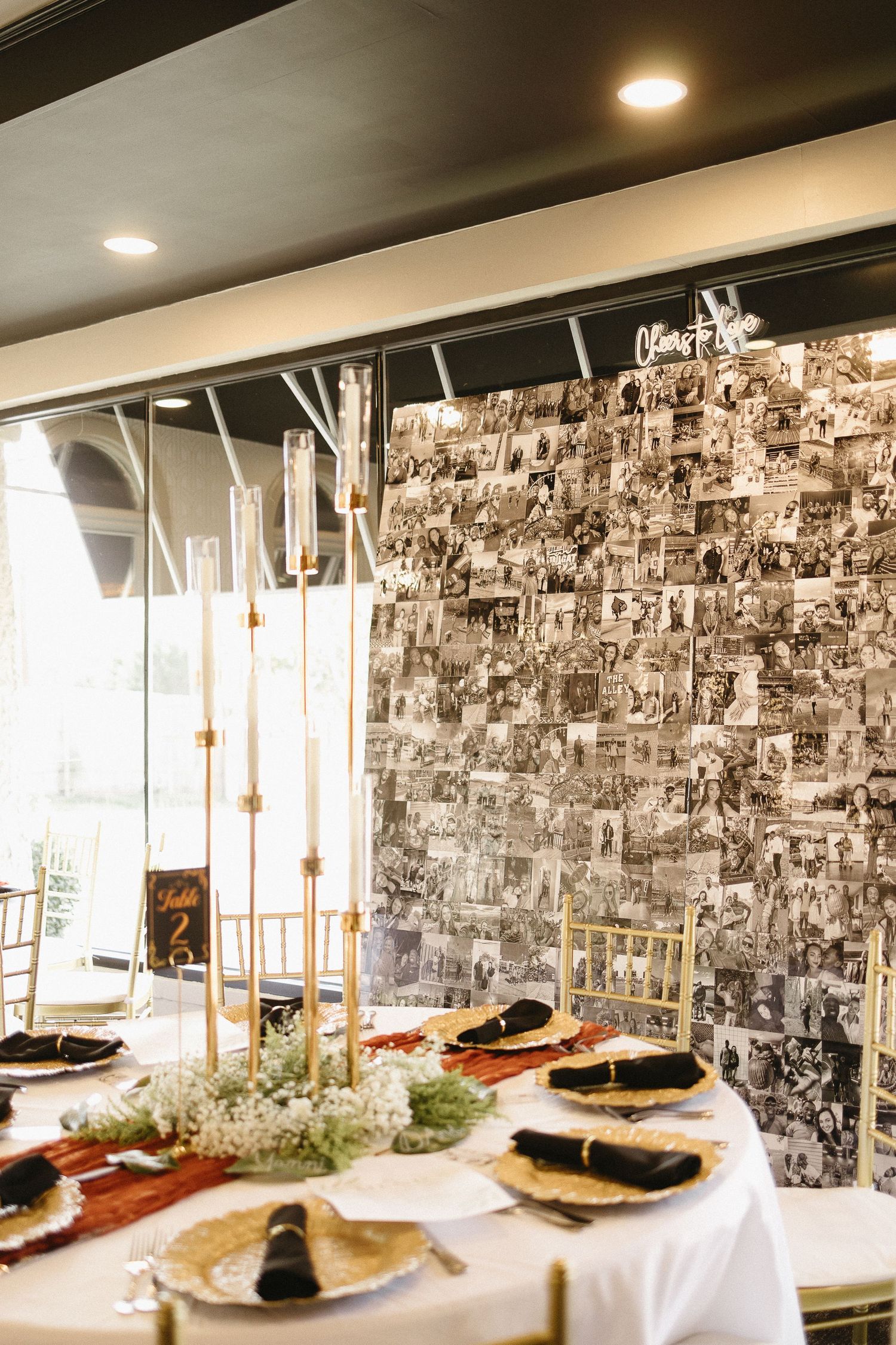 Elegant wedding reception buffet table with black and white photo wall backdrop.