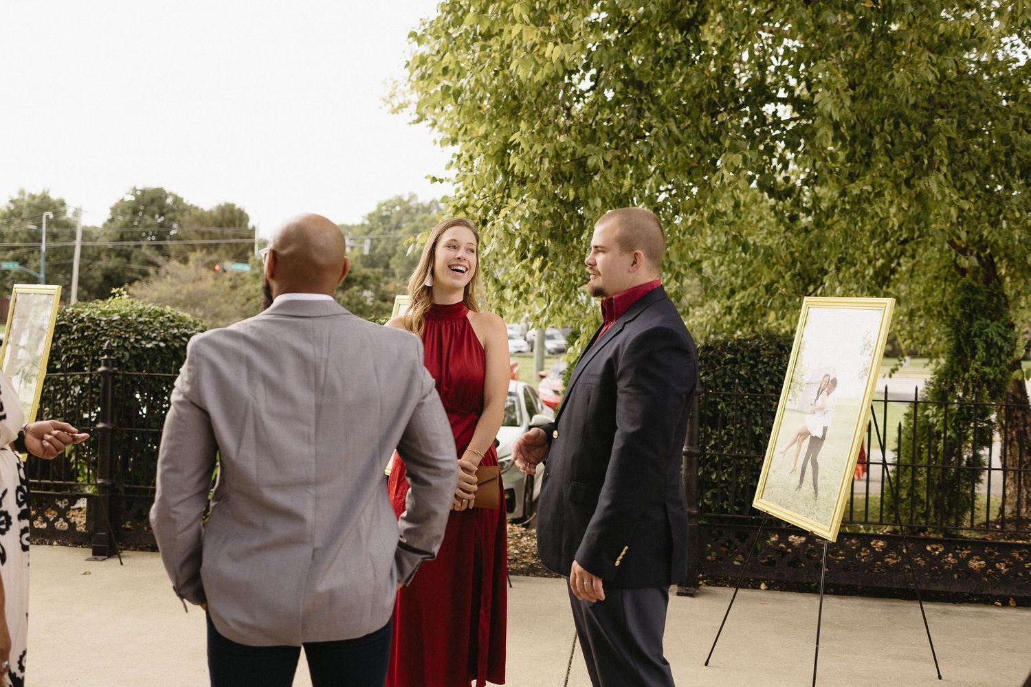 Guests engaging in conversation at outdoor wedding event with artwork displays.