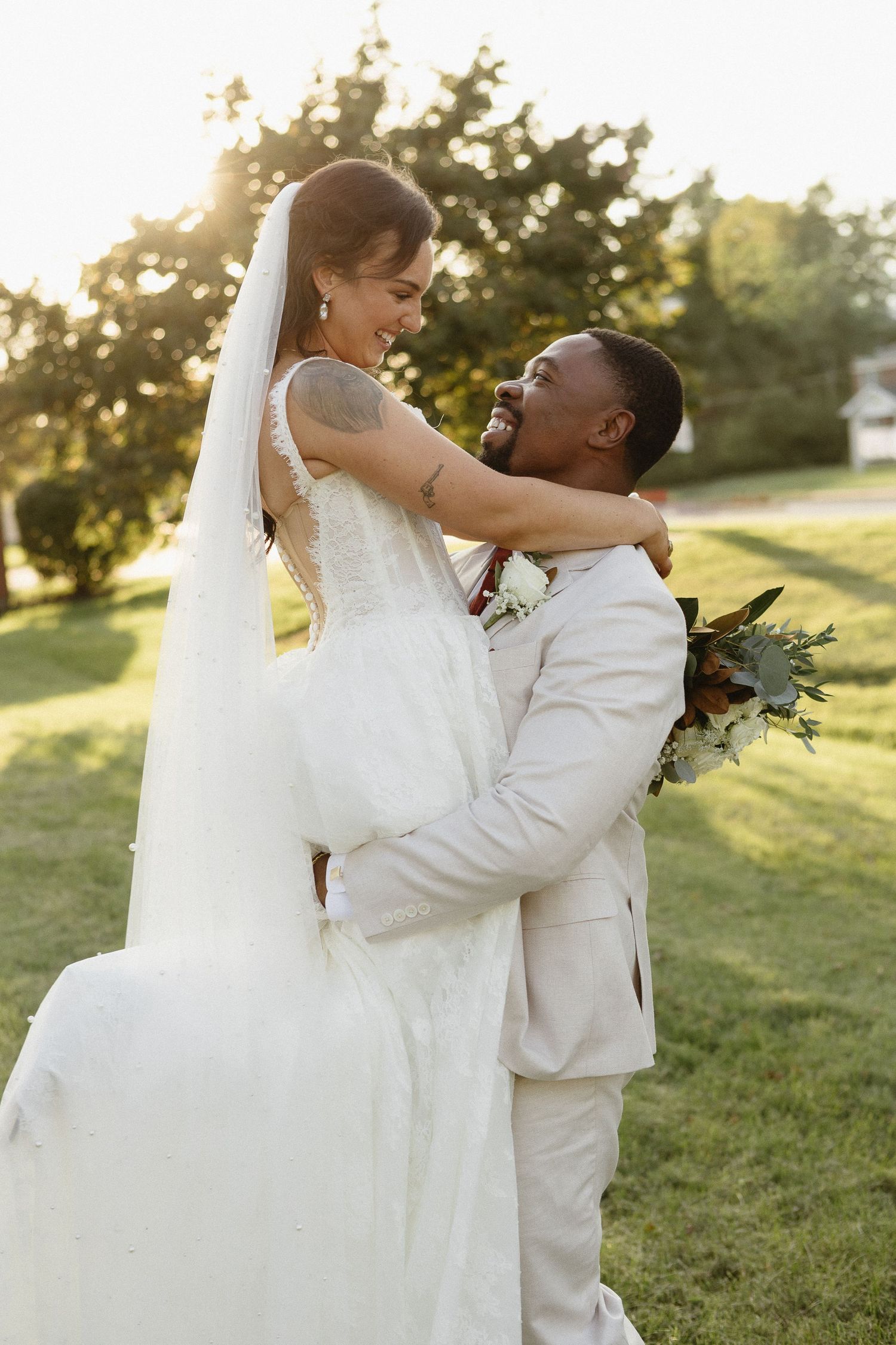 Couple shares romantic moments during sunset wedding photos on grassy hill.