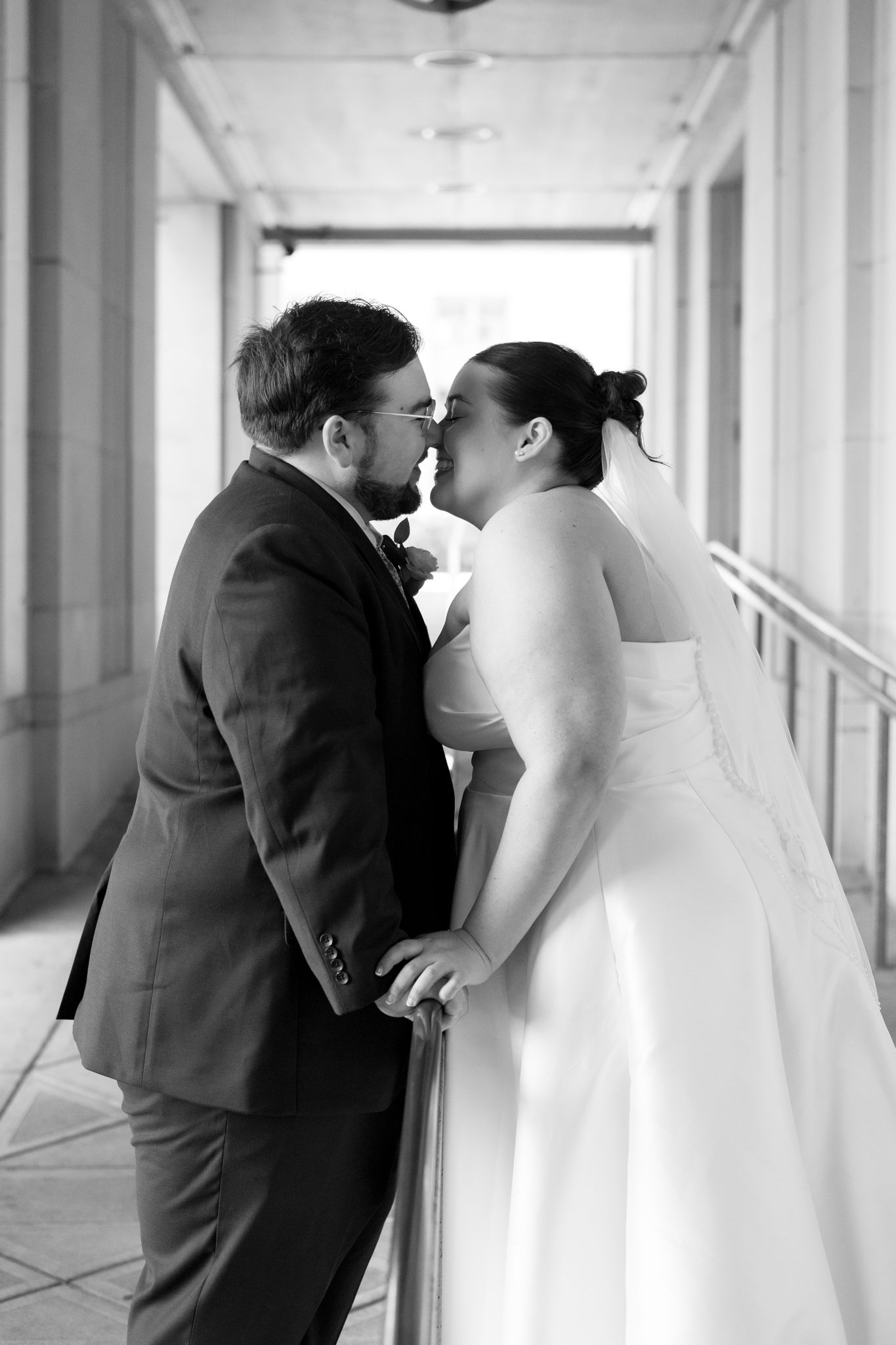 Black and white wedding photo series showing three romantic moments between newlyweds in a bright hallway.