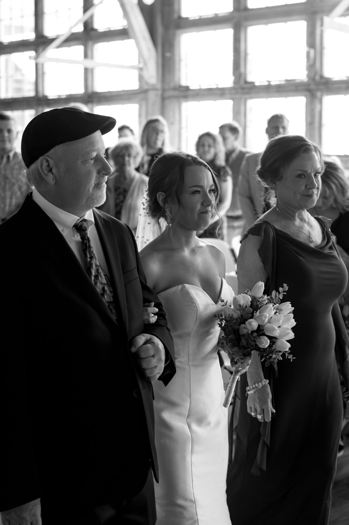 bride walking down the aisle at wedding with parents black and white photo