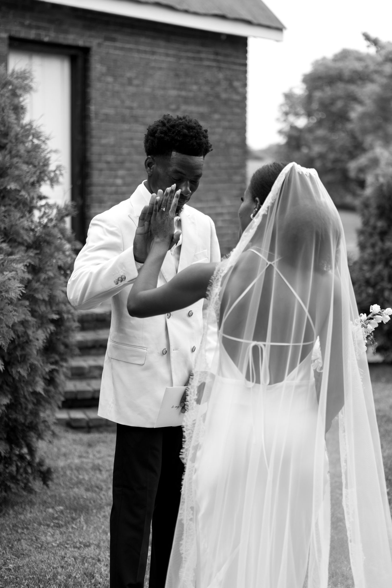 Black and white sequence of adjusting a flowing wedding veil outdoors.