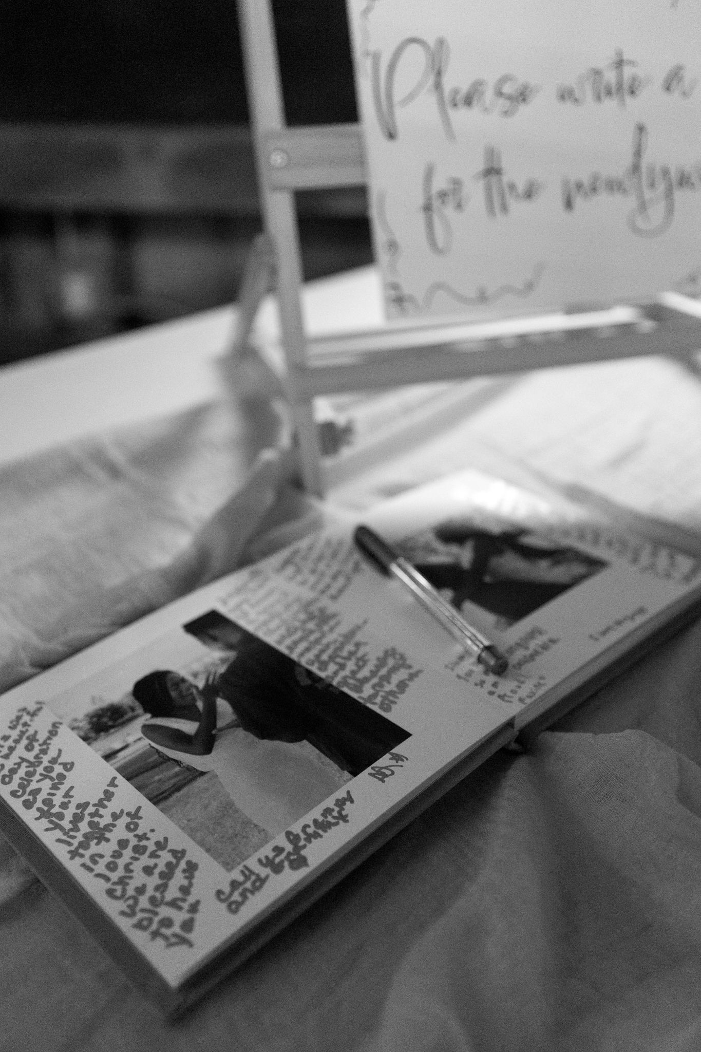 A black and white photo of an open guest book with handwritten messages and photos.