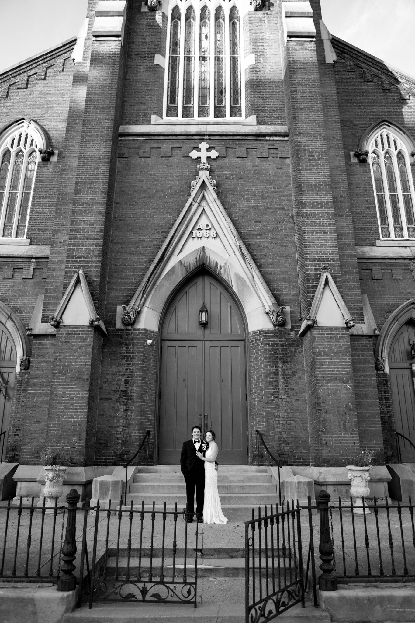 A historic brick church with Gothic architecture featuring pointed arches and ornate details in black and white.