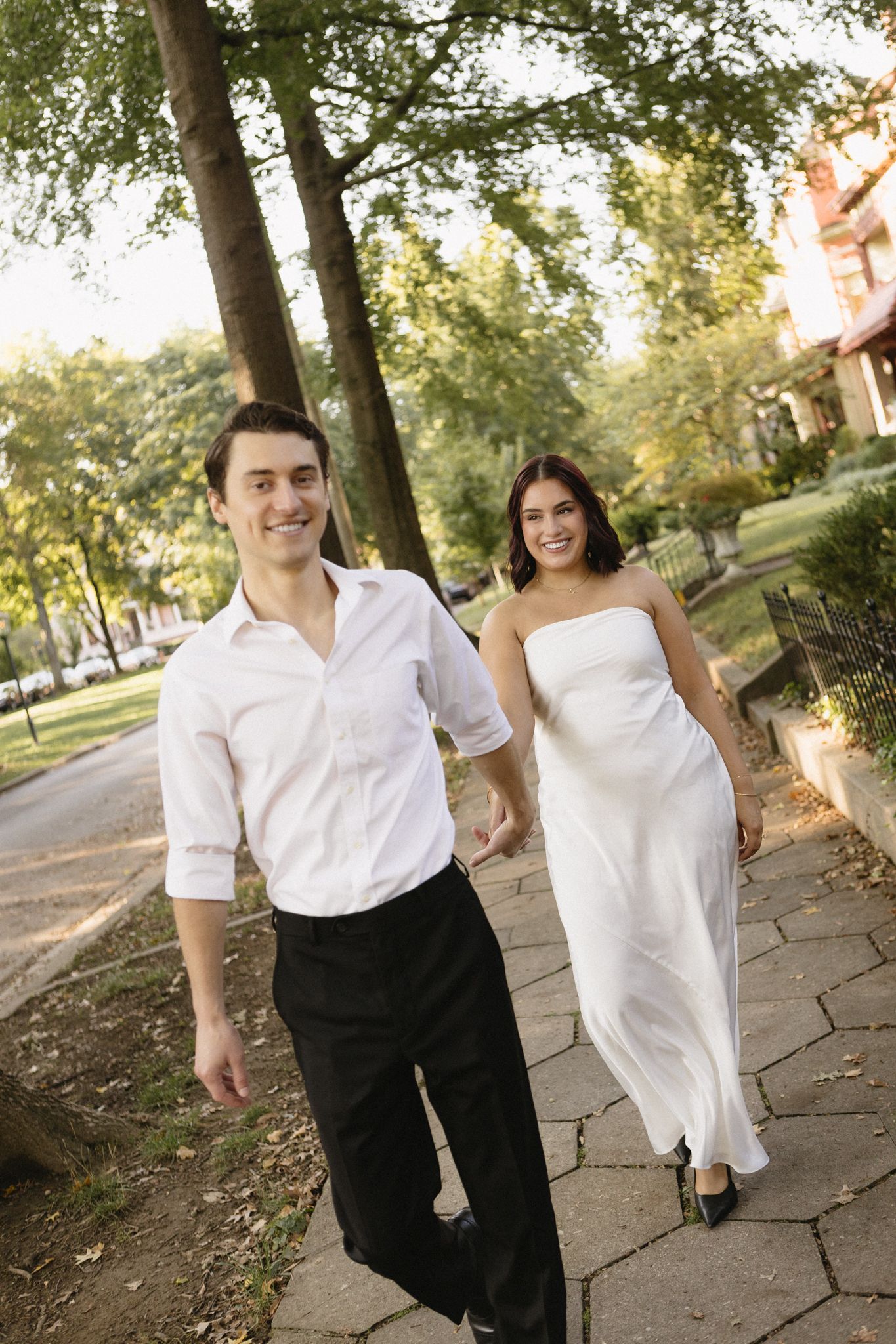 A couple walking together on a stone path, with the person in white wearing a flowing dress and the other in a white shirt.