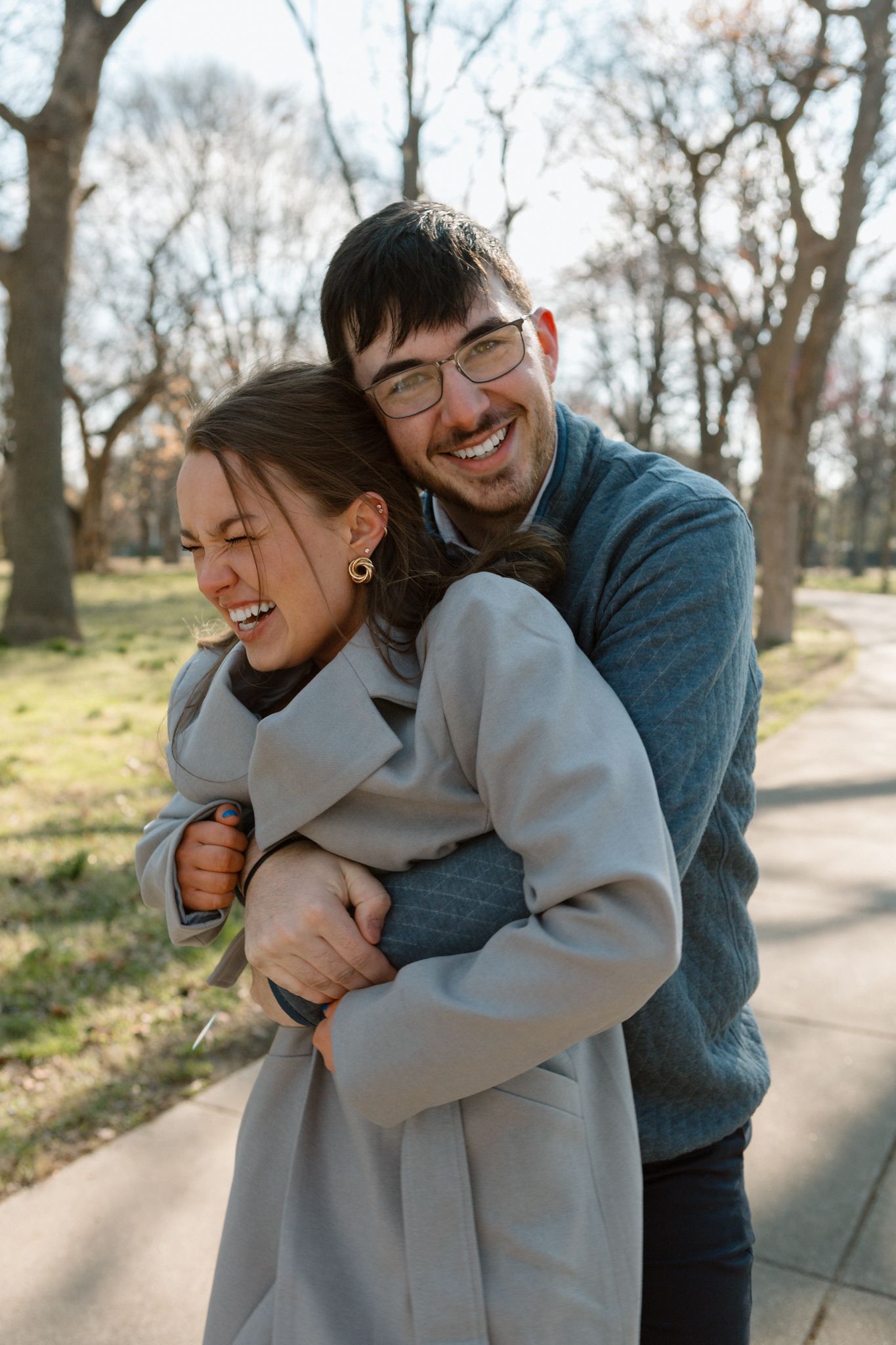 Engaged couple walking hand in hand down a historic street in Old Louisville on a crisp, cold day