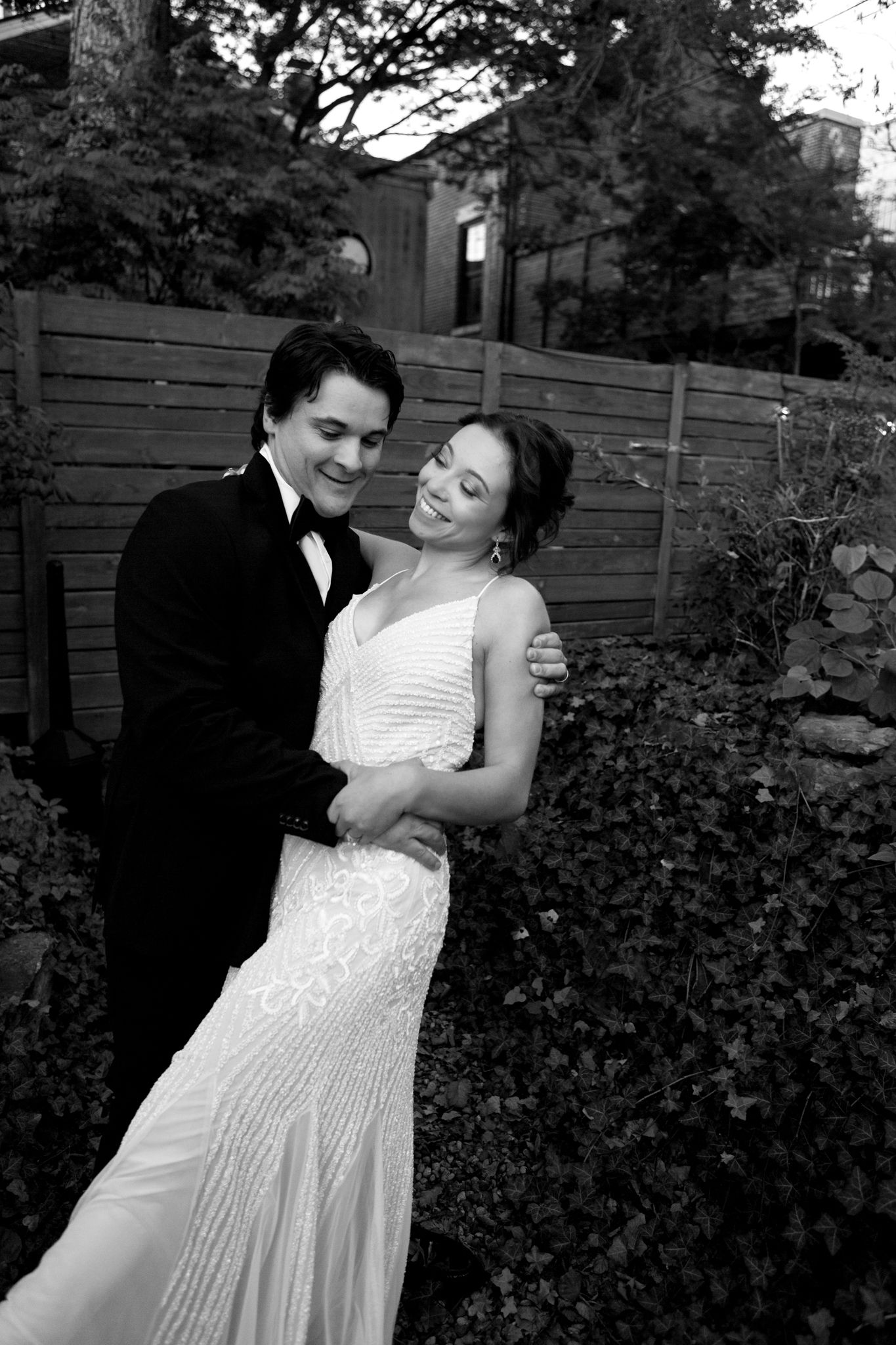 Romantic black and white portrait against wooden fence backdrop.