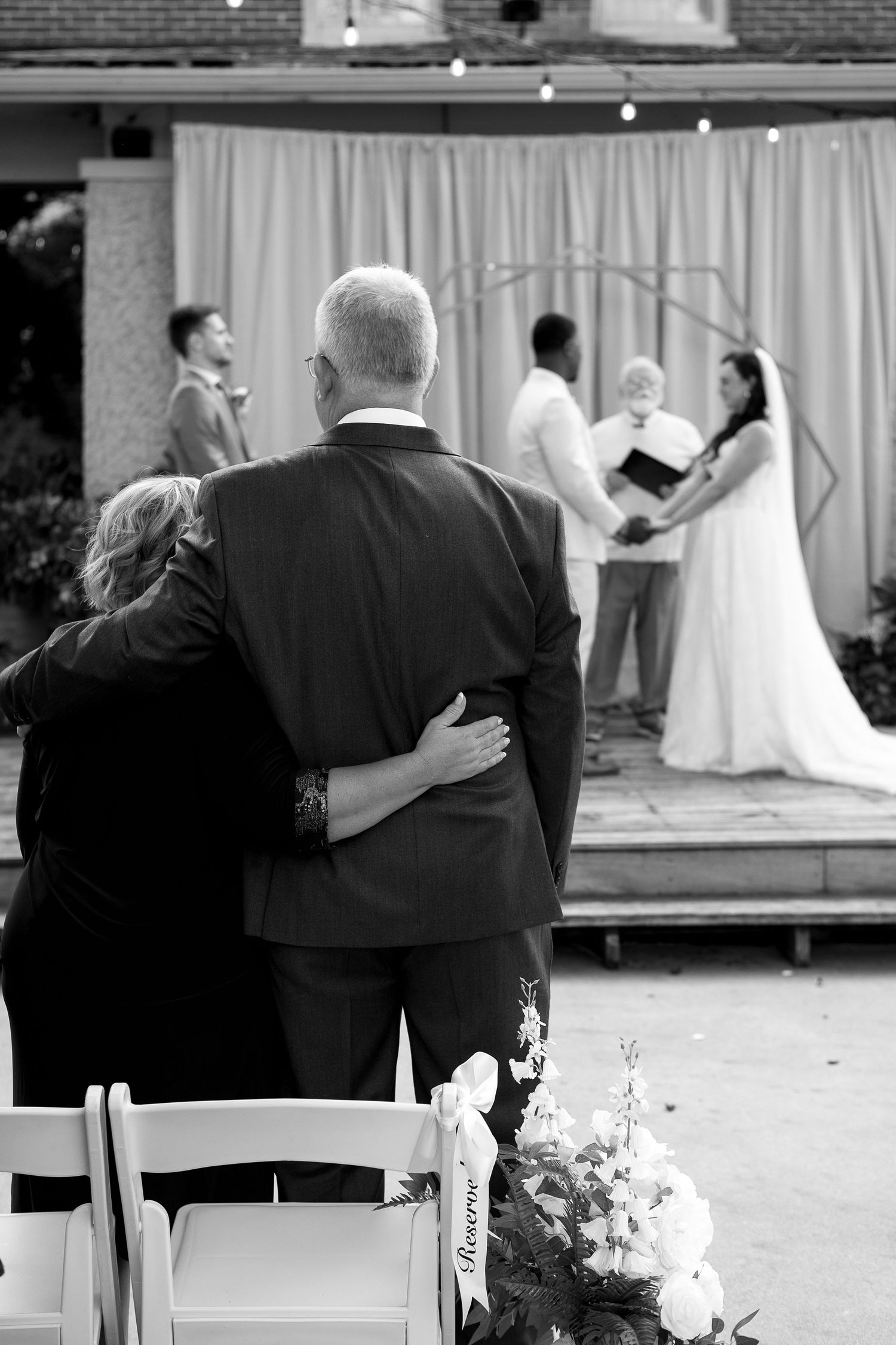 Black and white photo of emotional wedding ceremony moments with guests seated.