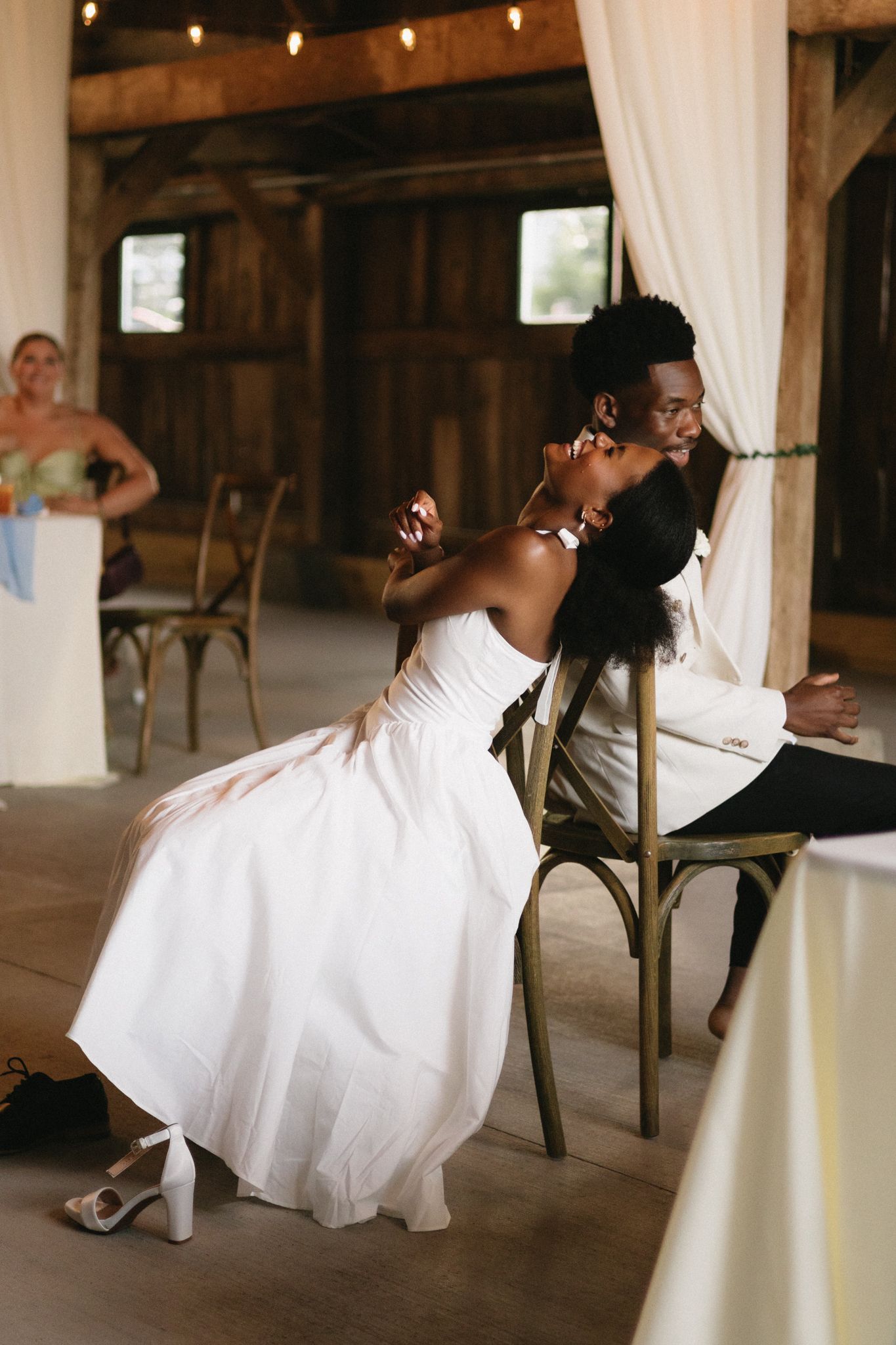Wedding couple dancing and dipping dramatically in a rustic barn setting with white drapes.
