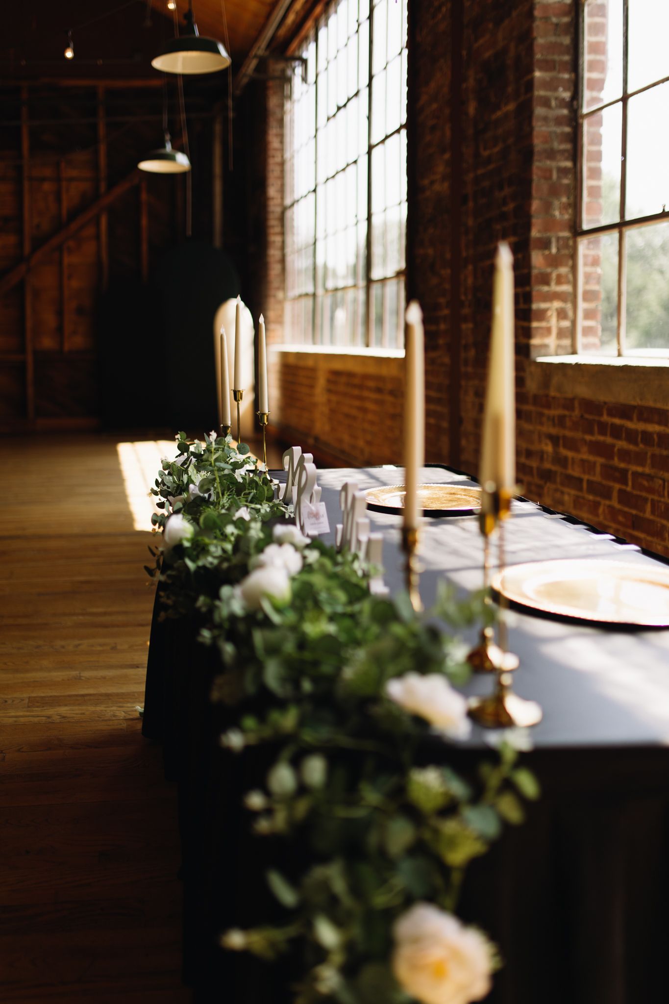 A long dining table elegantly decorated with candles and vibrant greenery, perfect for a cozy gathering