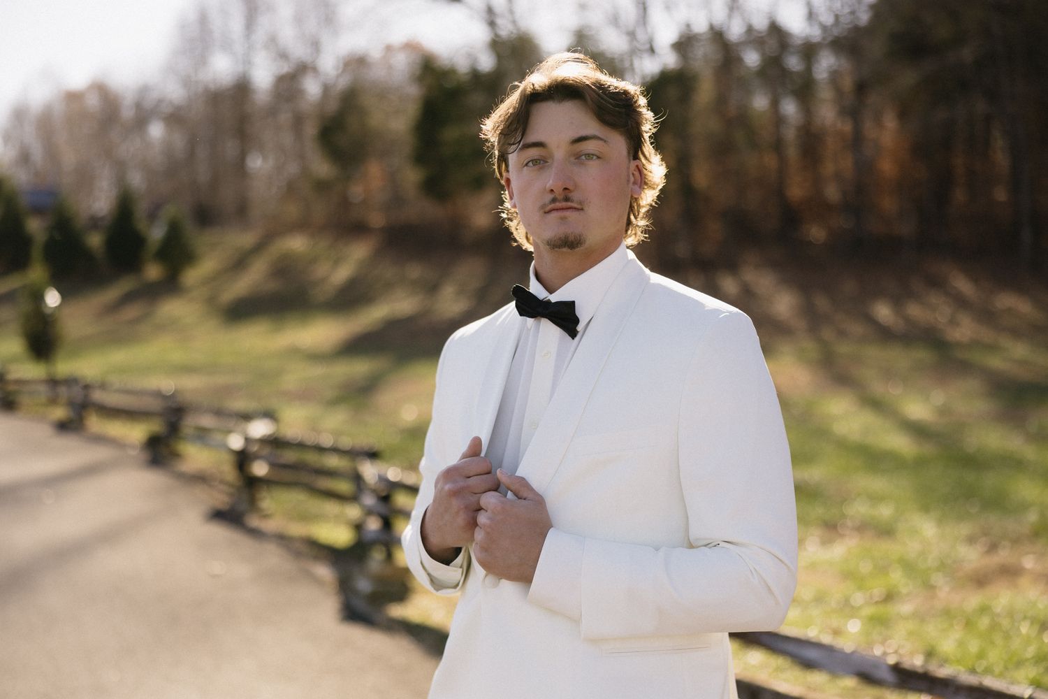 Groom in white dress shirt and black bow tie walking outdoors on wedding day.