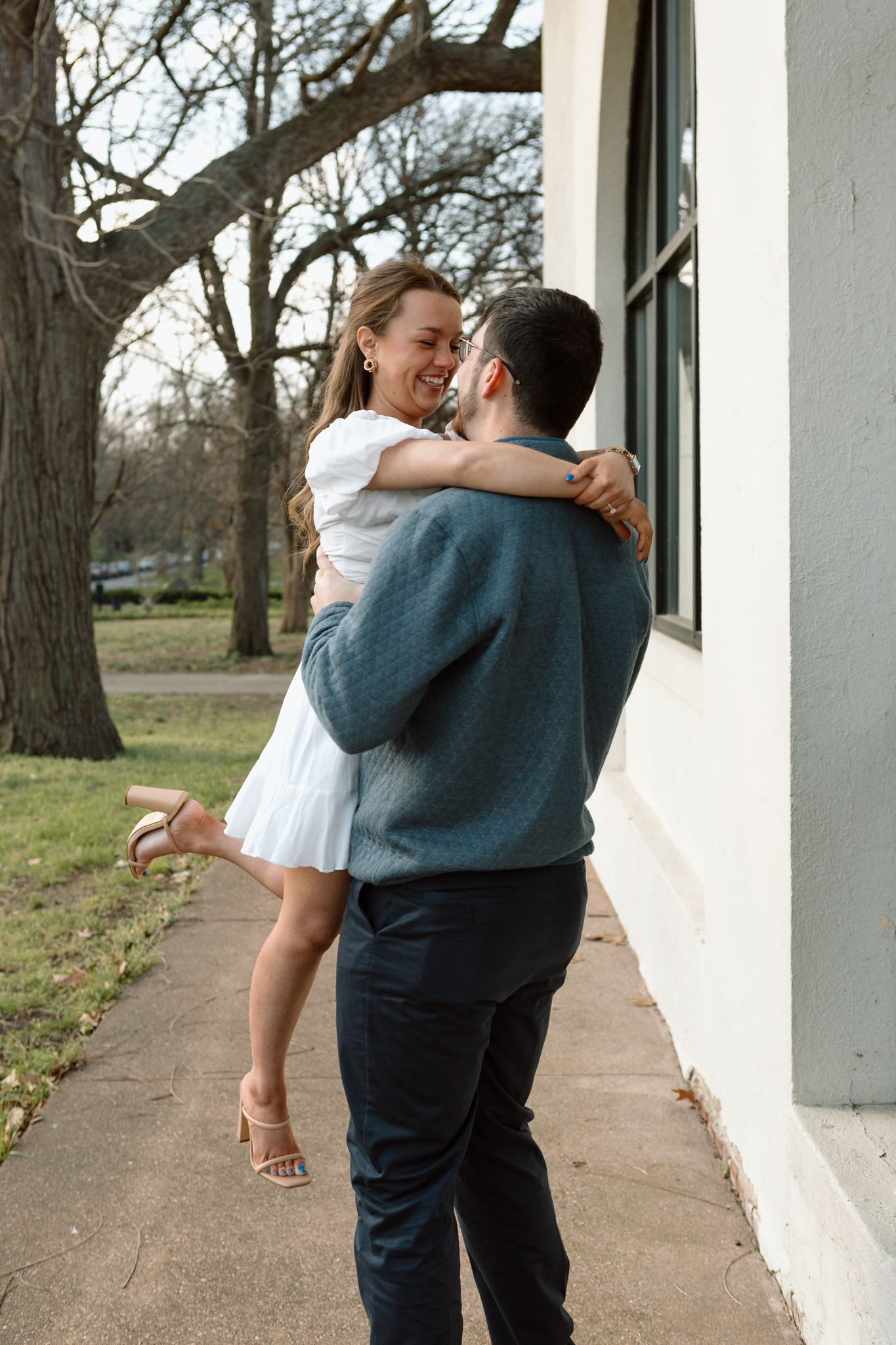 Chilly day engagement shoot in Old Louisville with couple embracing near iconic Victorian architecture.