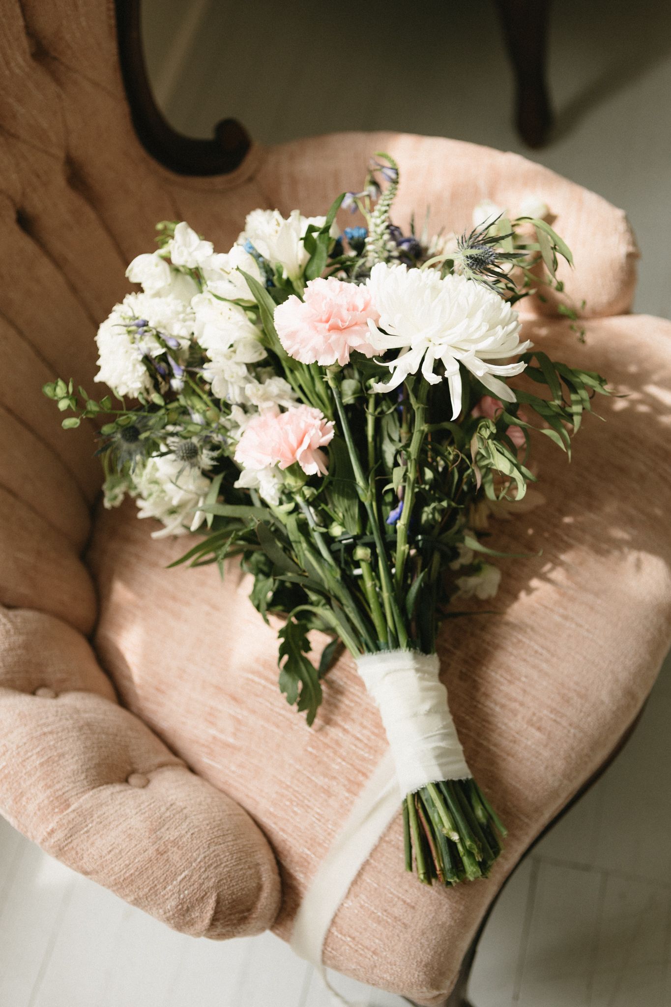 A series of photos showing white and pink daisies arranged in a bouquet against a soft beige fabric background.