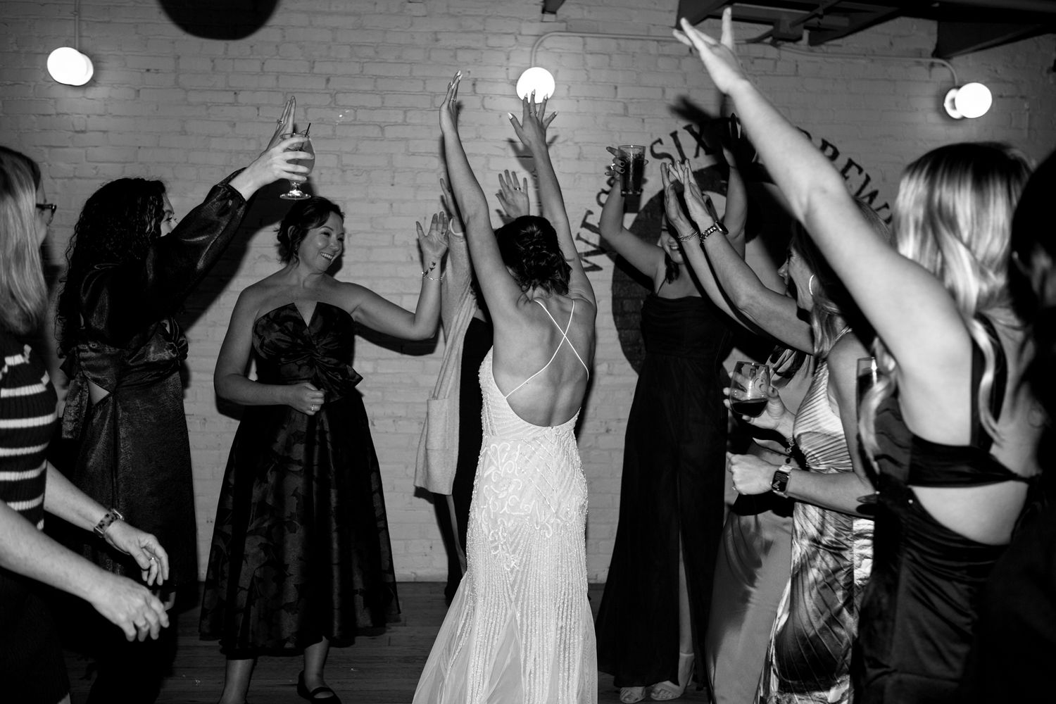 Wedding reception dance party showing silhouettes of people raising their arms on a dance floor.