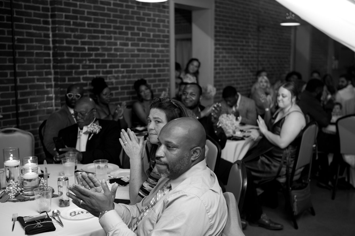 A group of formally dressed dinner guests engaged in animated conversation at a candlelit banquet table.