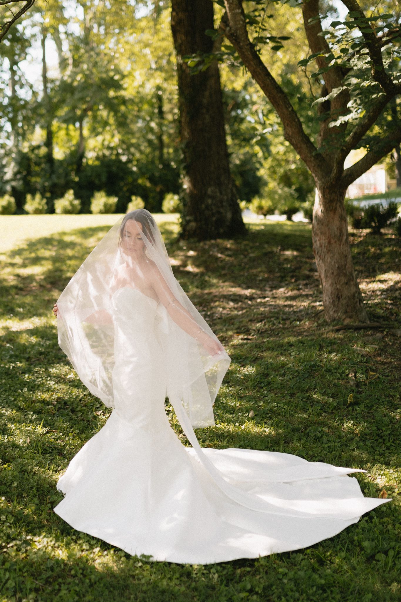 beautiful smiling bride standing on lush green grass around blooming flowers