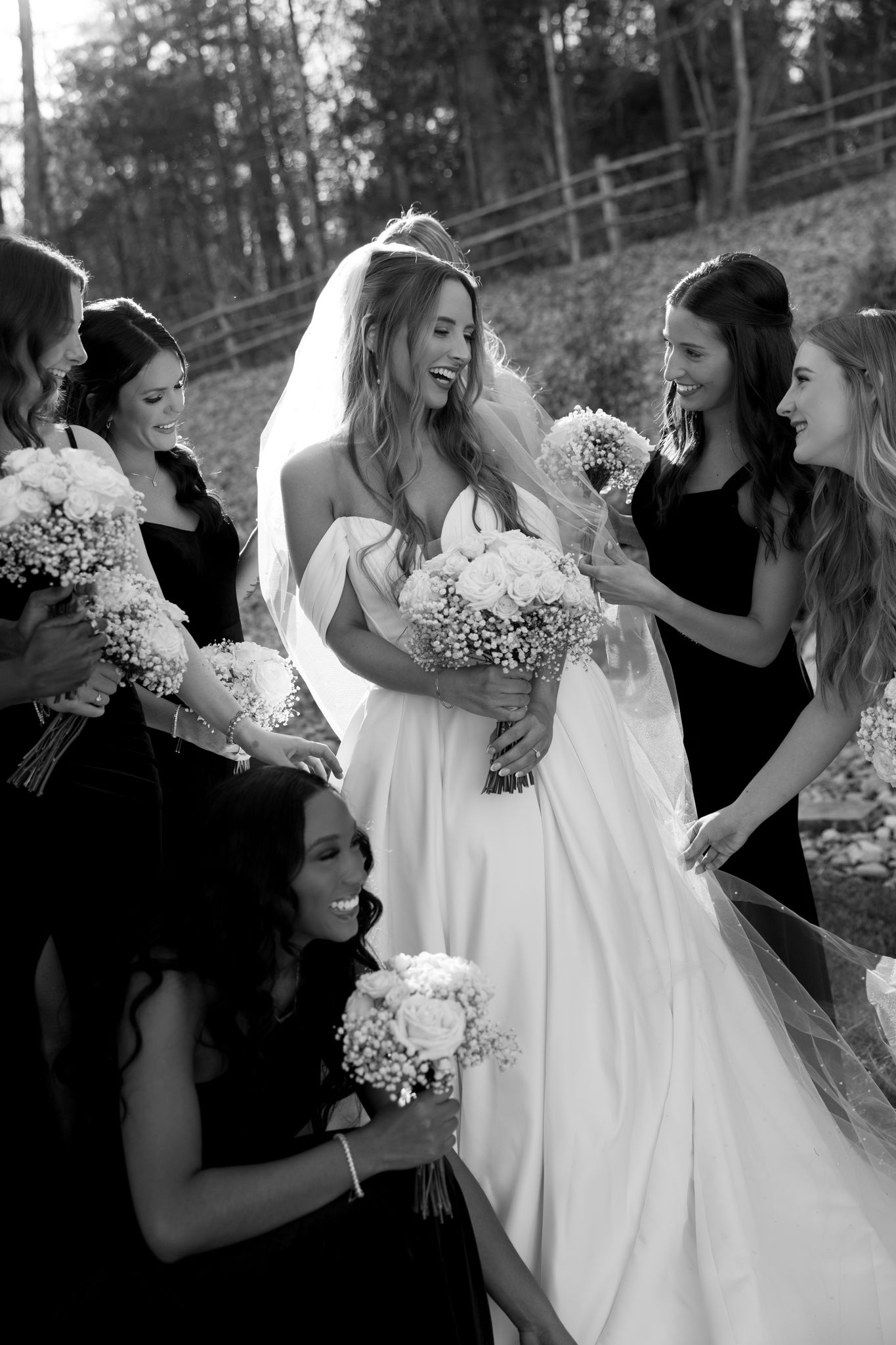 Black and white candid photos show bridesmaids in dark dresses helping adjust a bride's flowing white wedding gown.
