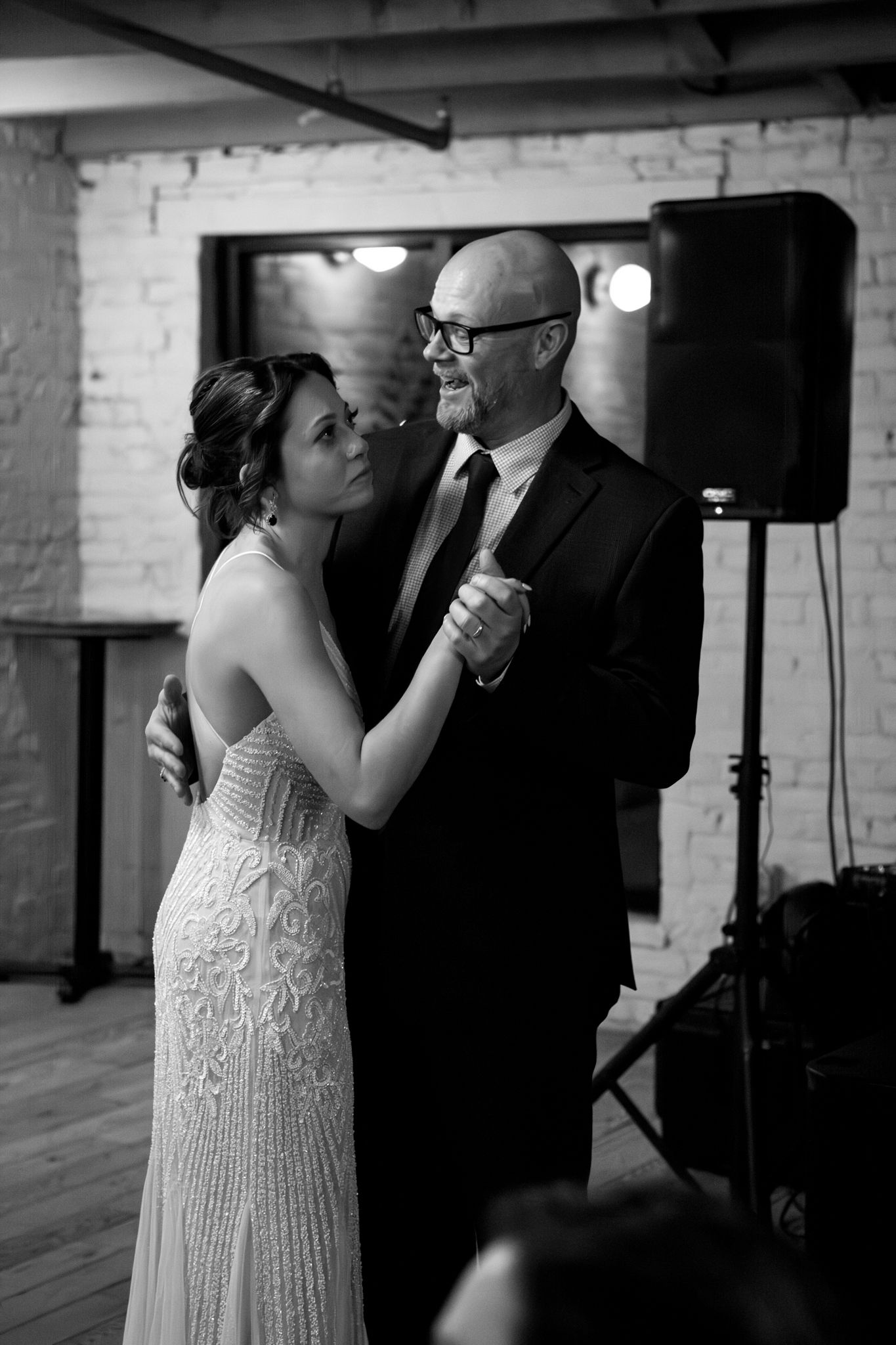 An emotional father-daughter dance captured in black and white during a wedding reception.