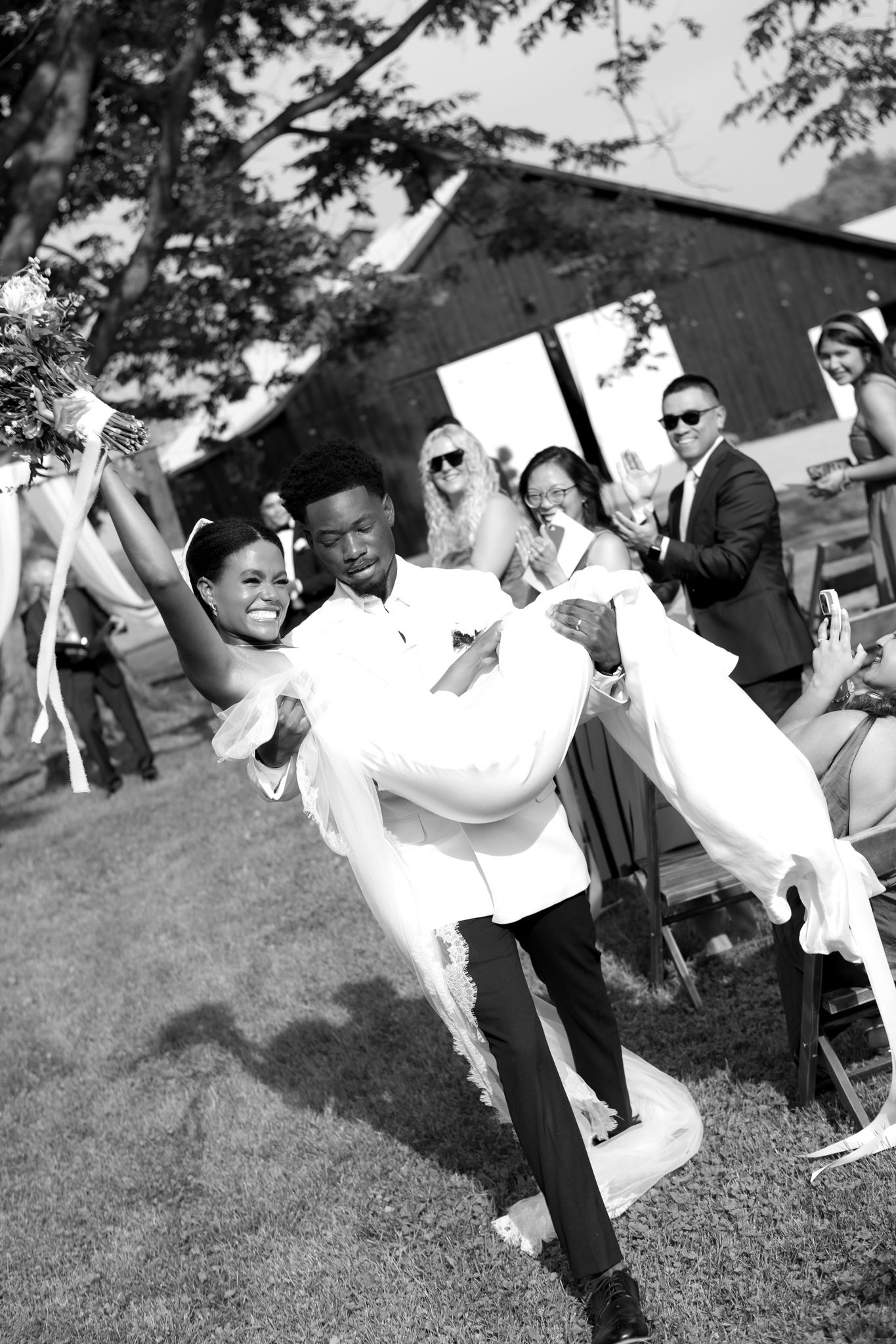 Wedding guests celebrating and dancing joyfully on the grass at an outdoor reception.