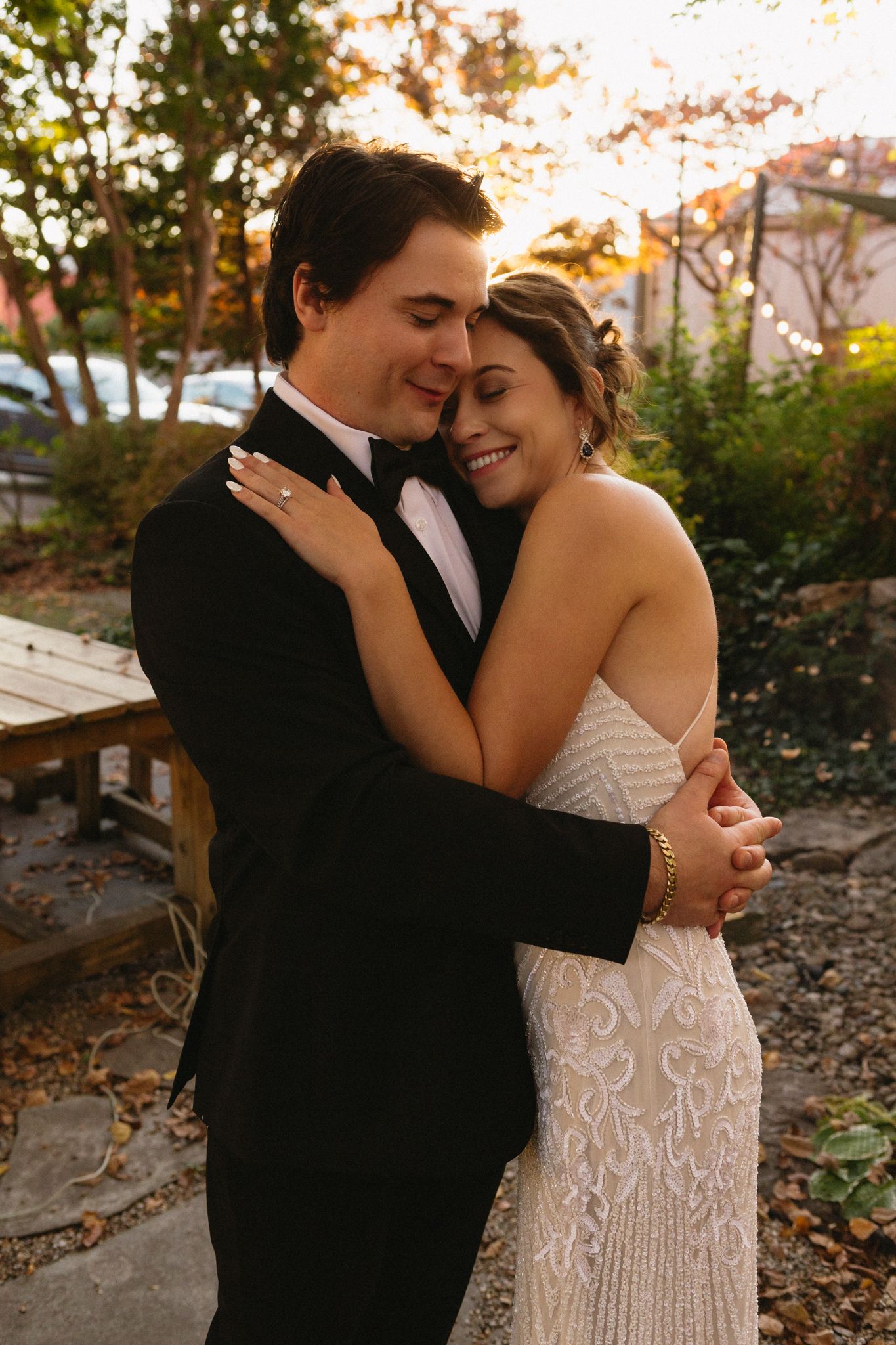 A tender moment between a couple in formal attire embracing outdoors during golden hour.