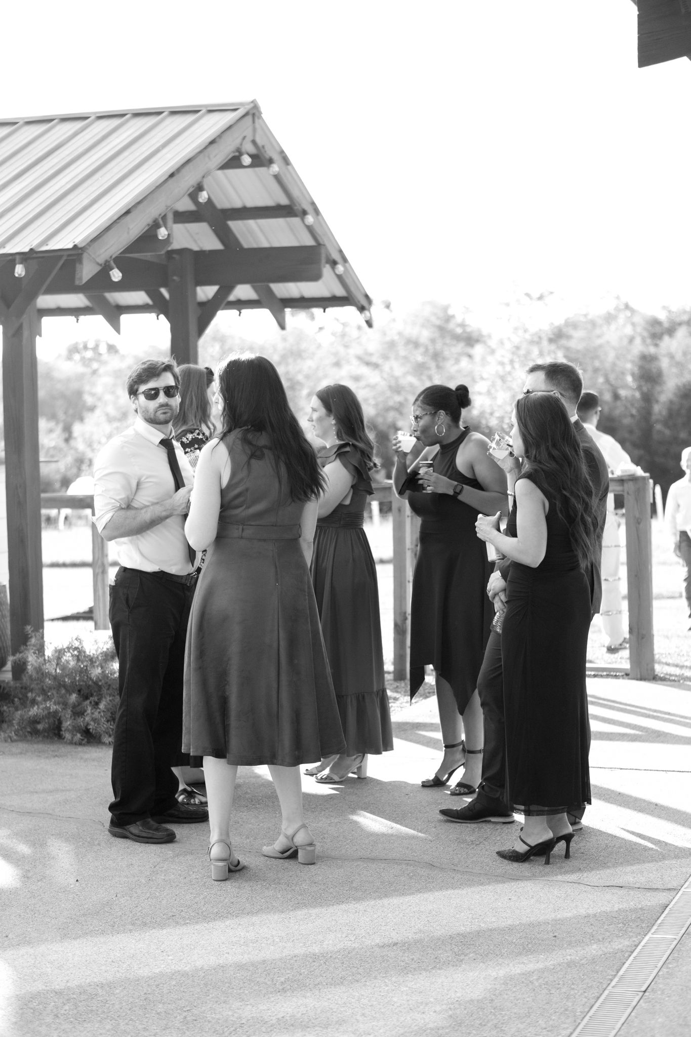 A group gathers under a covered outdoor pavilion for a social event.