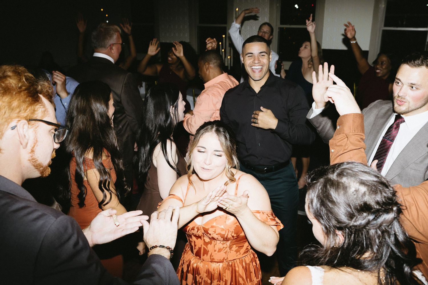 People dancing and socializing at a crowded party or nightclub event with dark lighting.