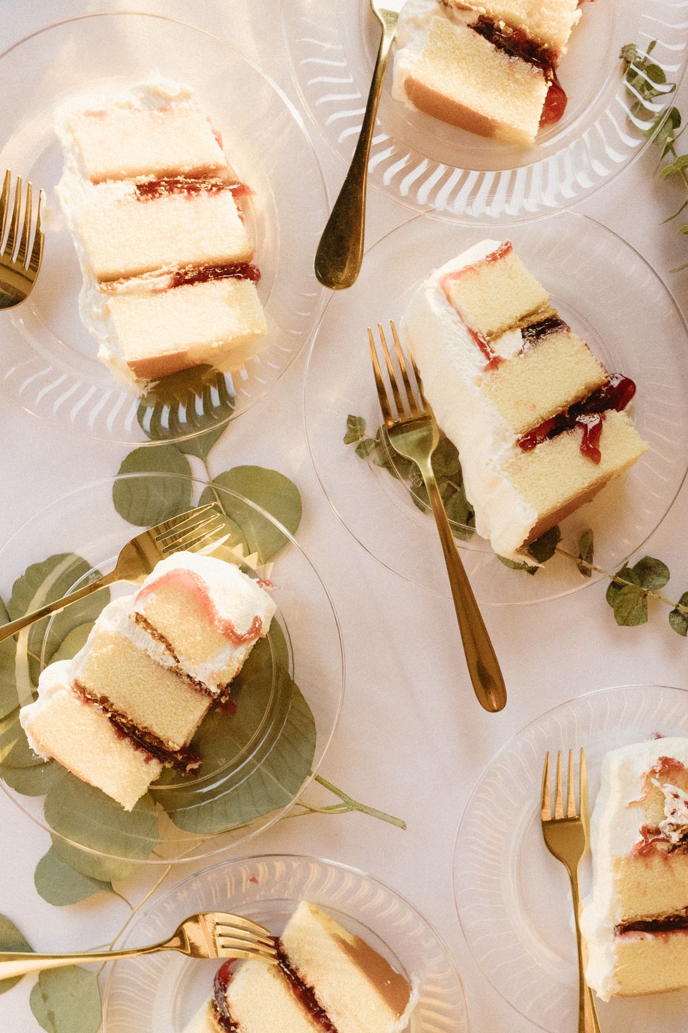Wedding cake slices with delicate garnish on decorative plates with eucalyptus leaves.