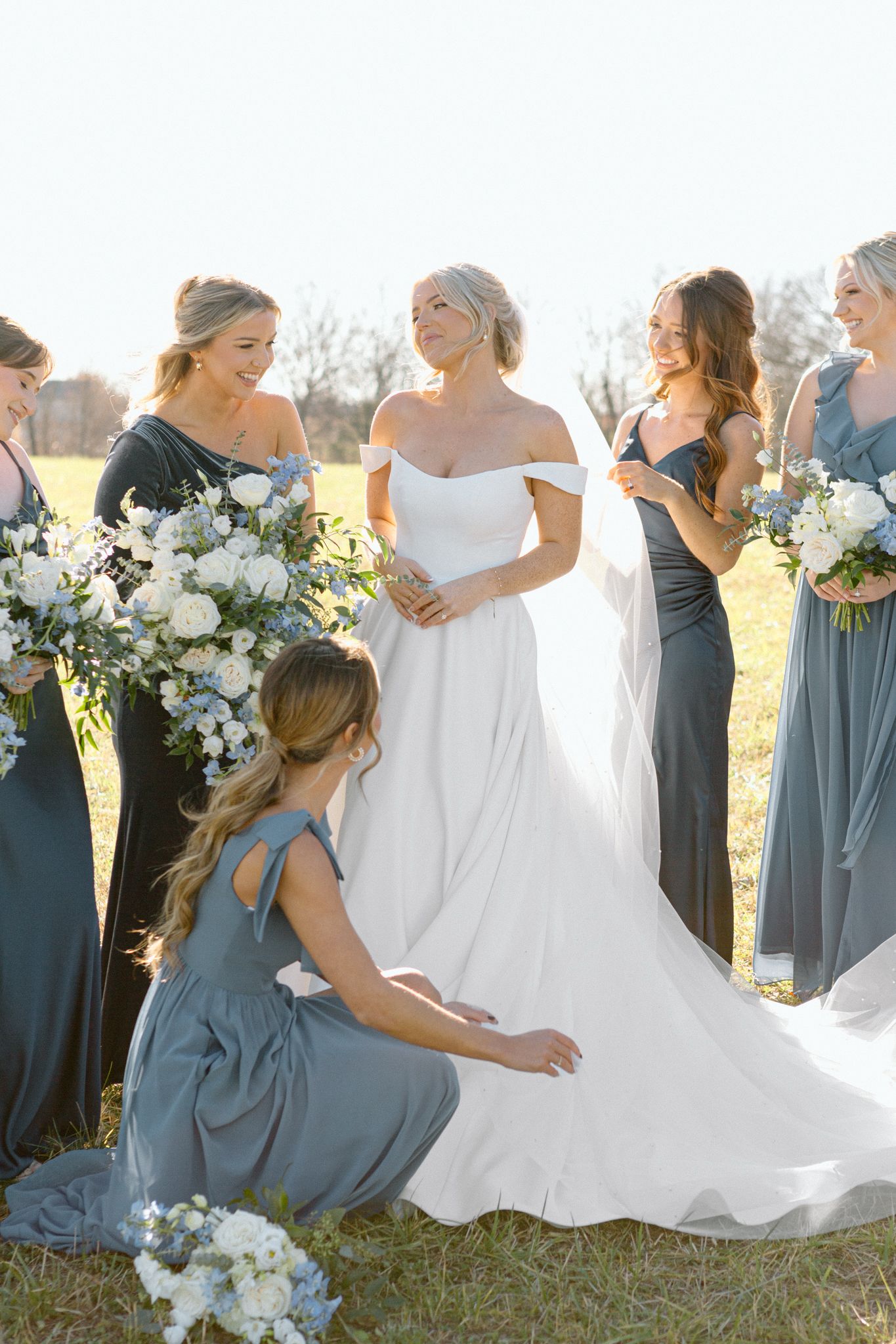 Smiling bride and bridesmaids in elegant wedding attire, posing together outdoors