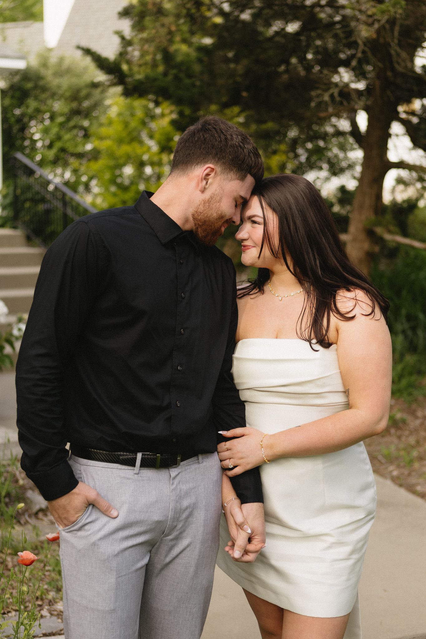 A romantic couple in coordinated black and white outfits share an intimate moment outdoors.