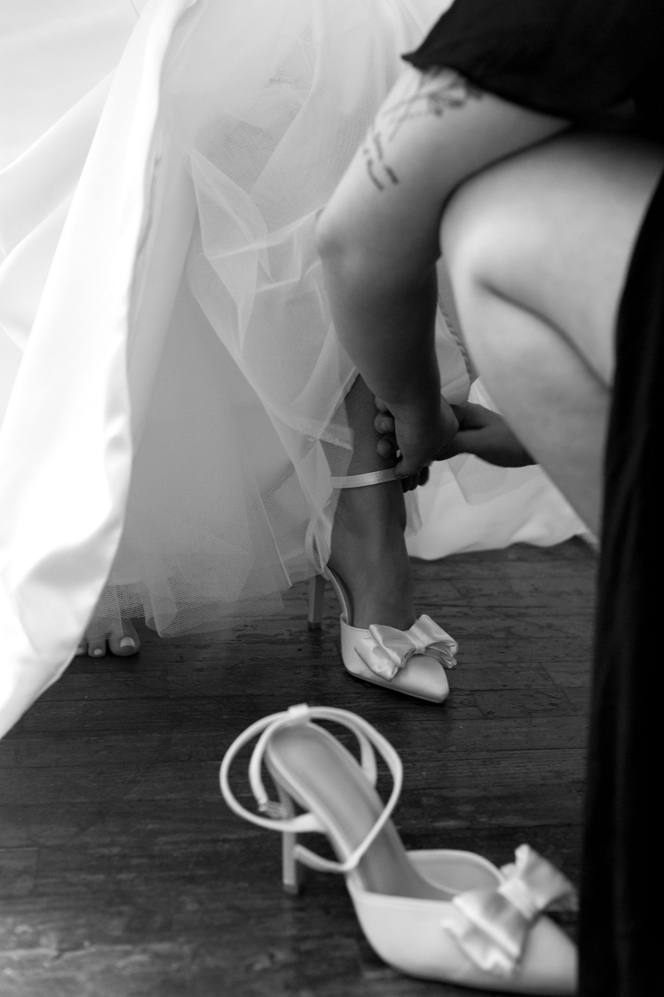 A woman lovingly helps a bride into her wedding dress, symbolizing friendship and the beauty of shared moments before th