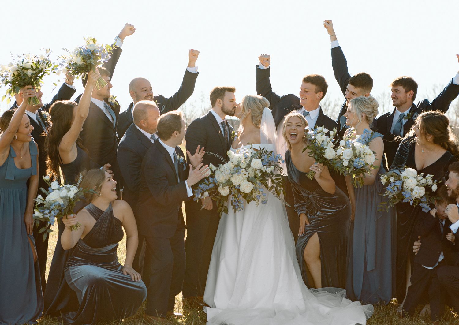 Bride, groom, and entire bridal party posing together for a joyful wedding photo
