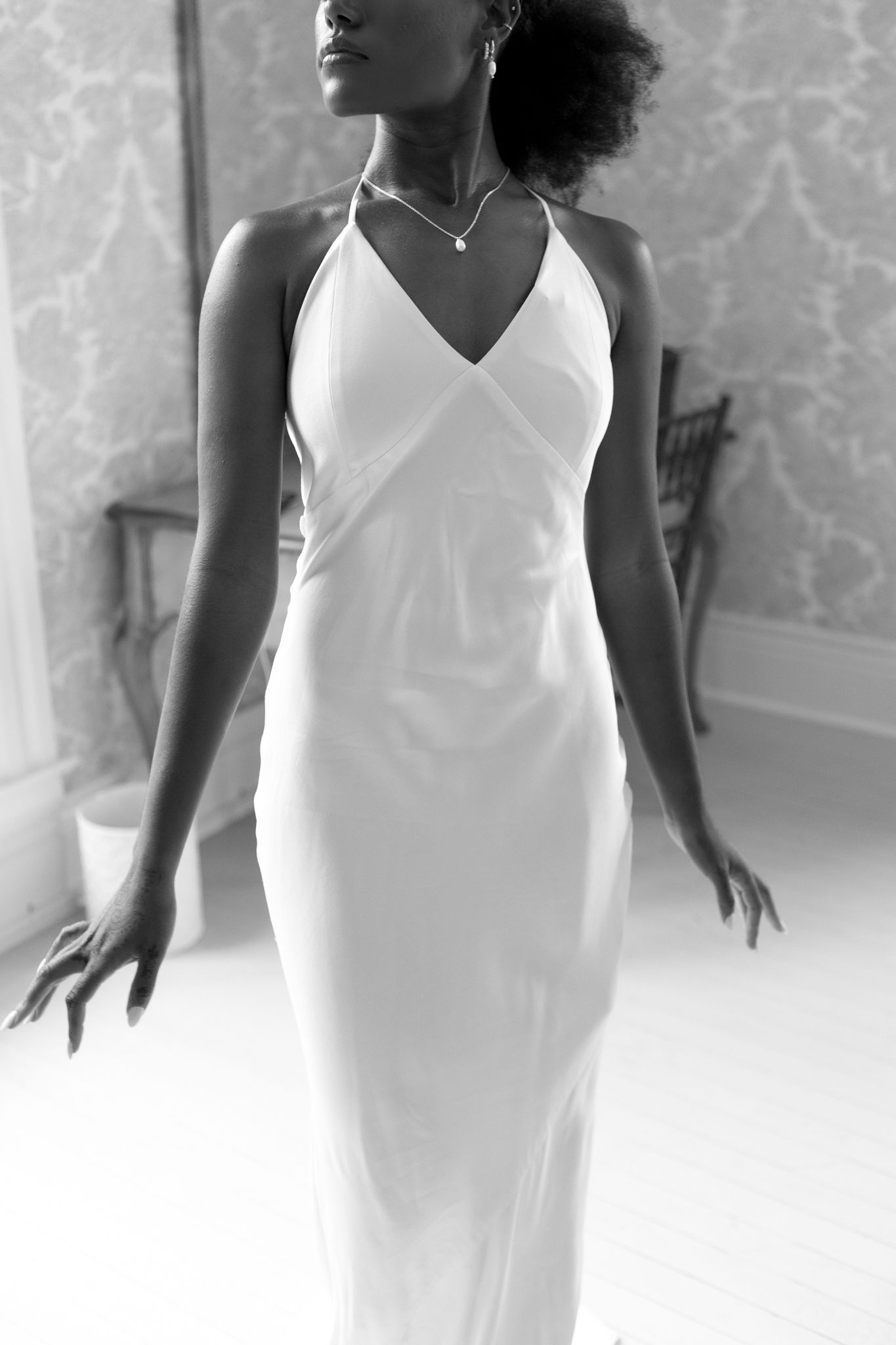 Elegant white dress with v-neckline shown in multiple artistic angles against light wallpaper background.