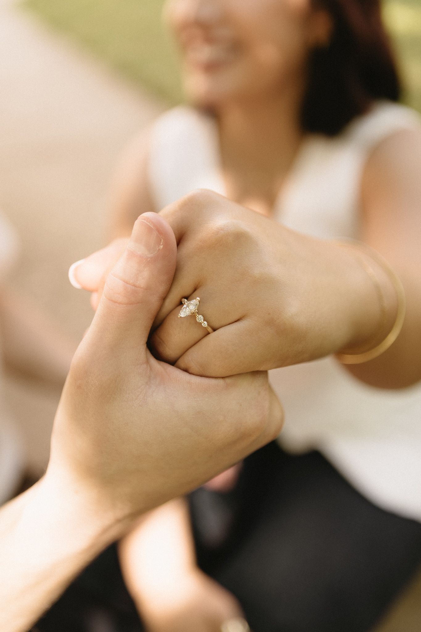 A close-up sequence of hands joining together in a pinky promise gesture, with one hand wearing an engagement ring.