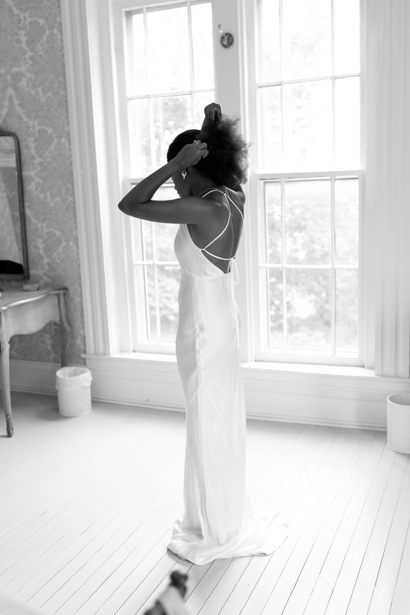 Motion blur captures graceful dance movements in a bright white sunlit room with large windows.