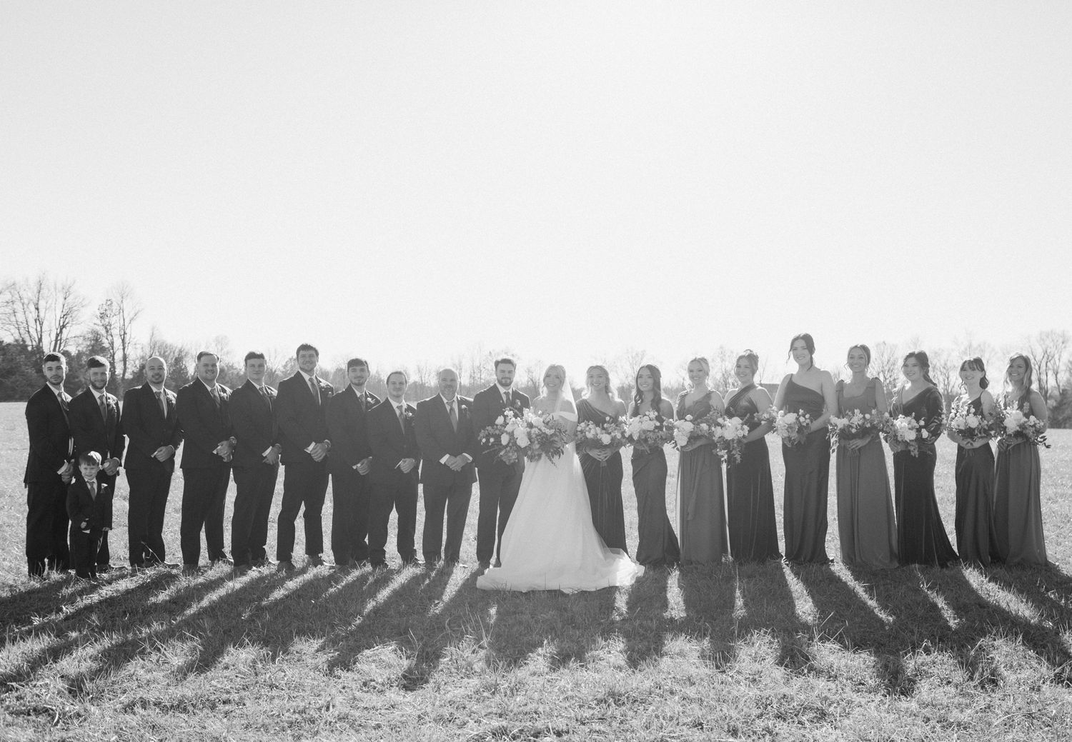 Bride, groom, and entire bridal party posing together for a joyful wedding photo