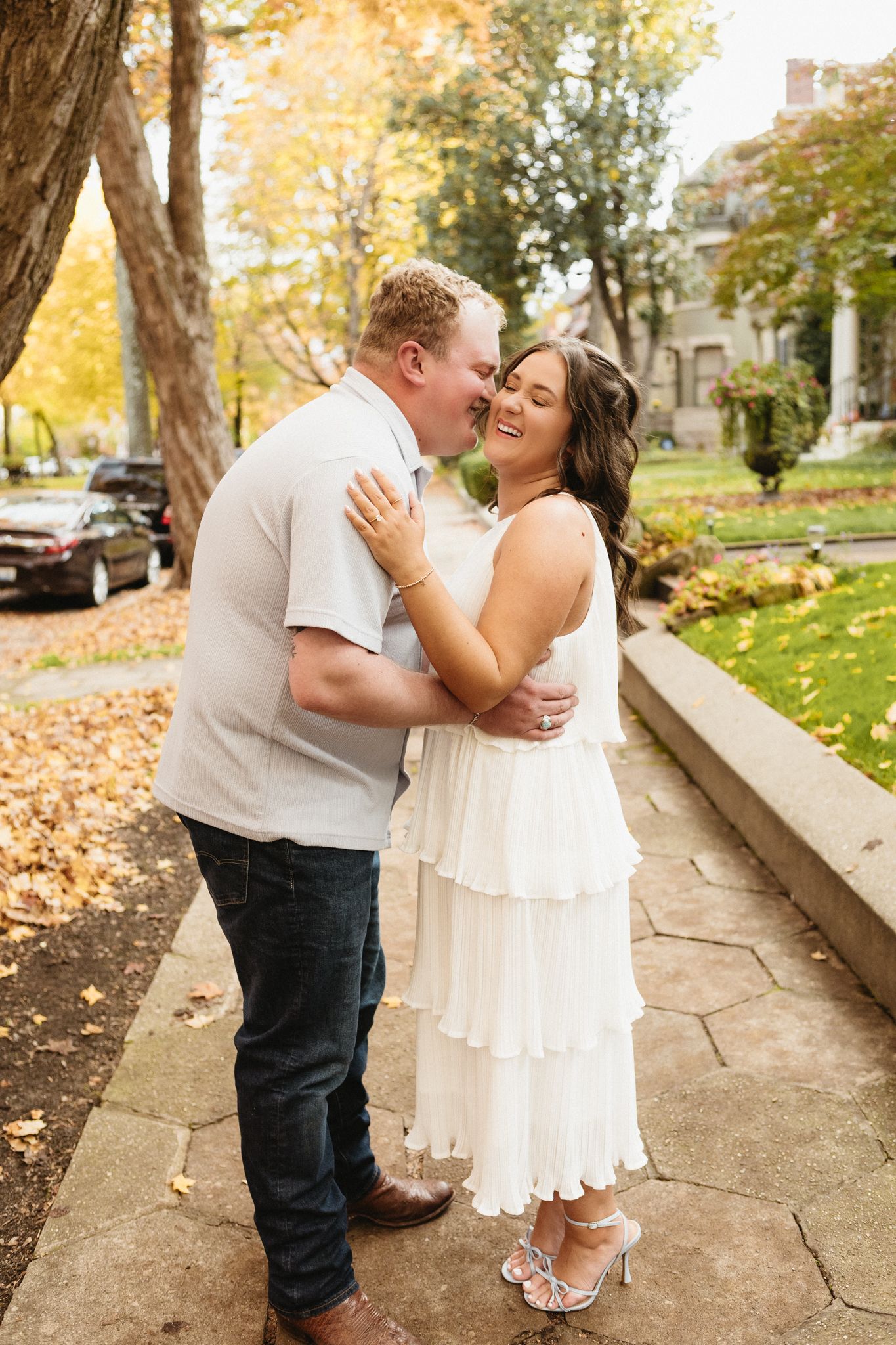 A couple shares a romantic moment on a stone path surrounded by fall foliage and autumn colors.