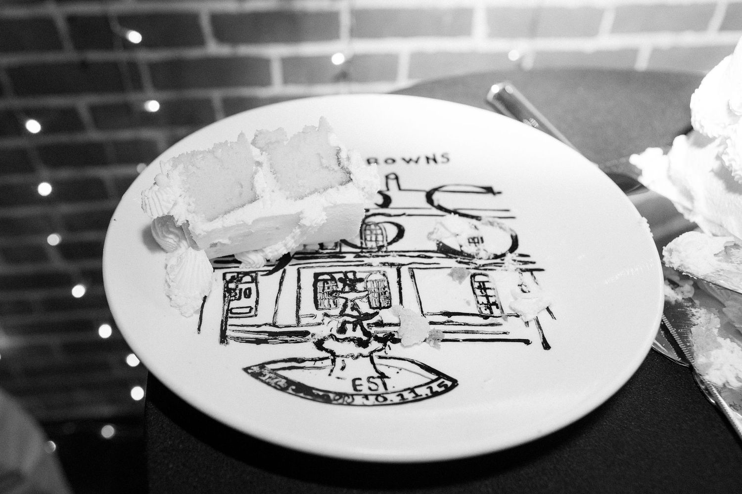 Black and white artistic plates with whimsical line drawings displayed against brick wall.